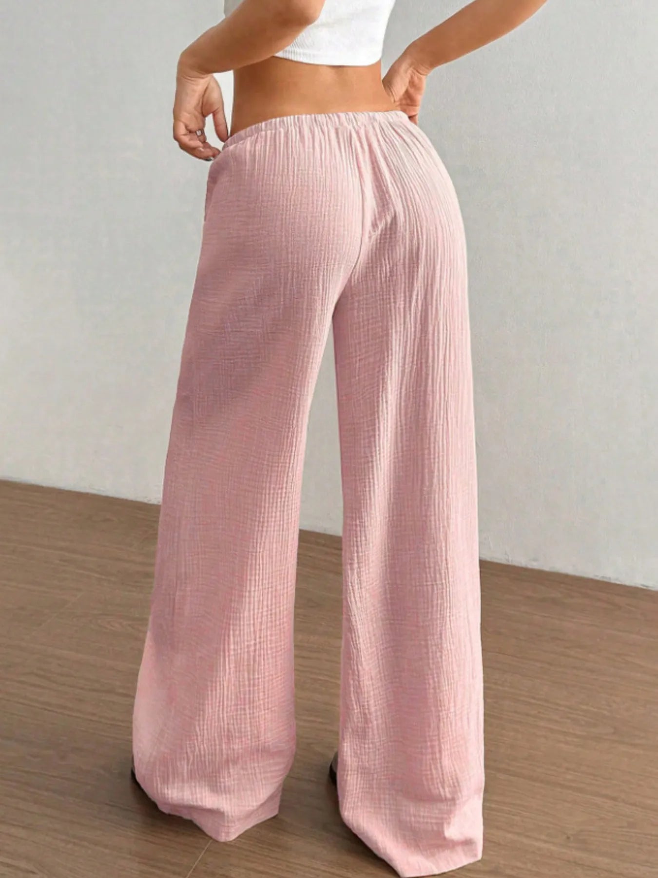 Person wearing light pink wide-leg pants on a plain background