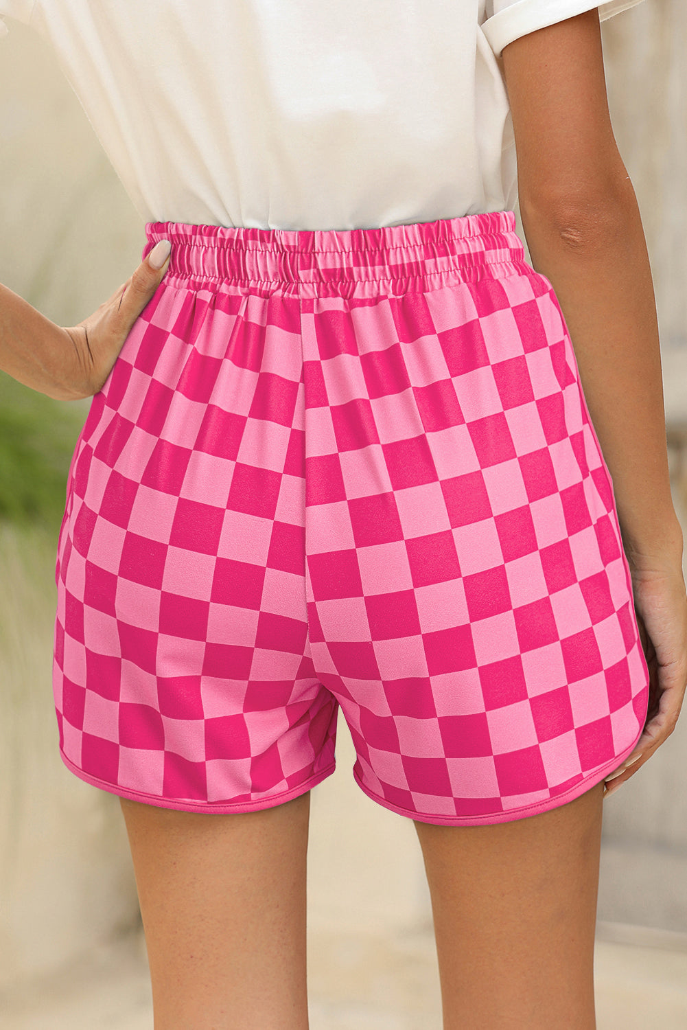 Pink checkered shorts worn by a person with a blurred background