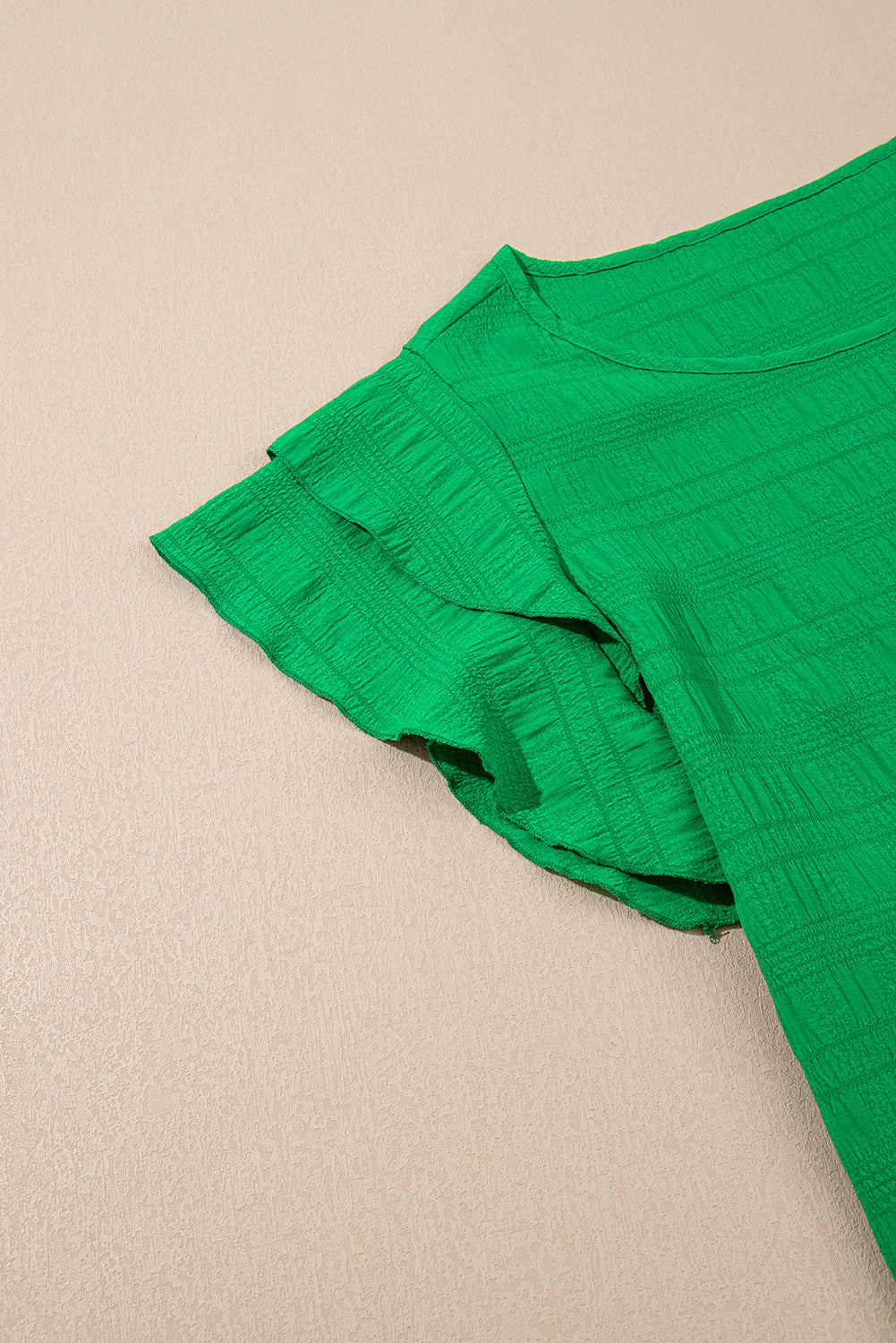 Green fabric with ruffled edge on a beige background