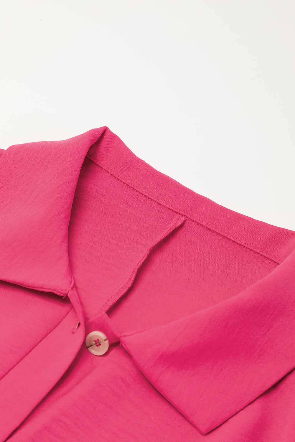 Close-up of a pink garment with a button on a light gray background