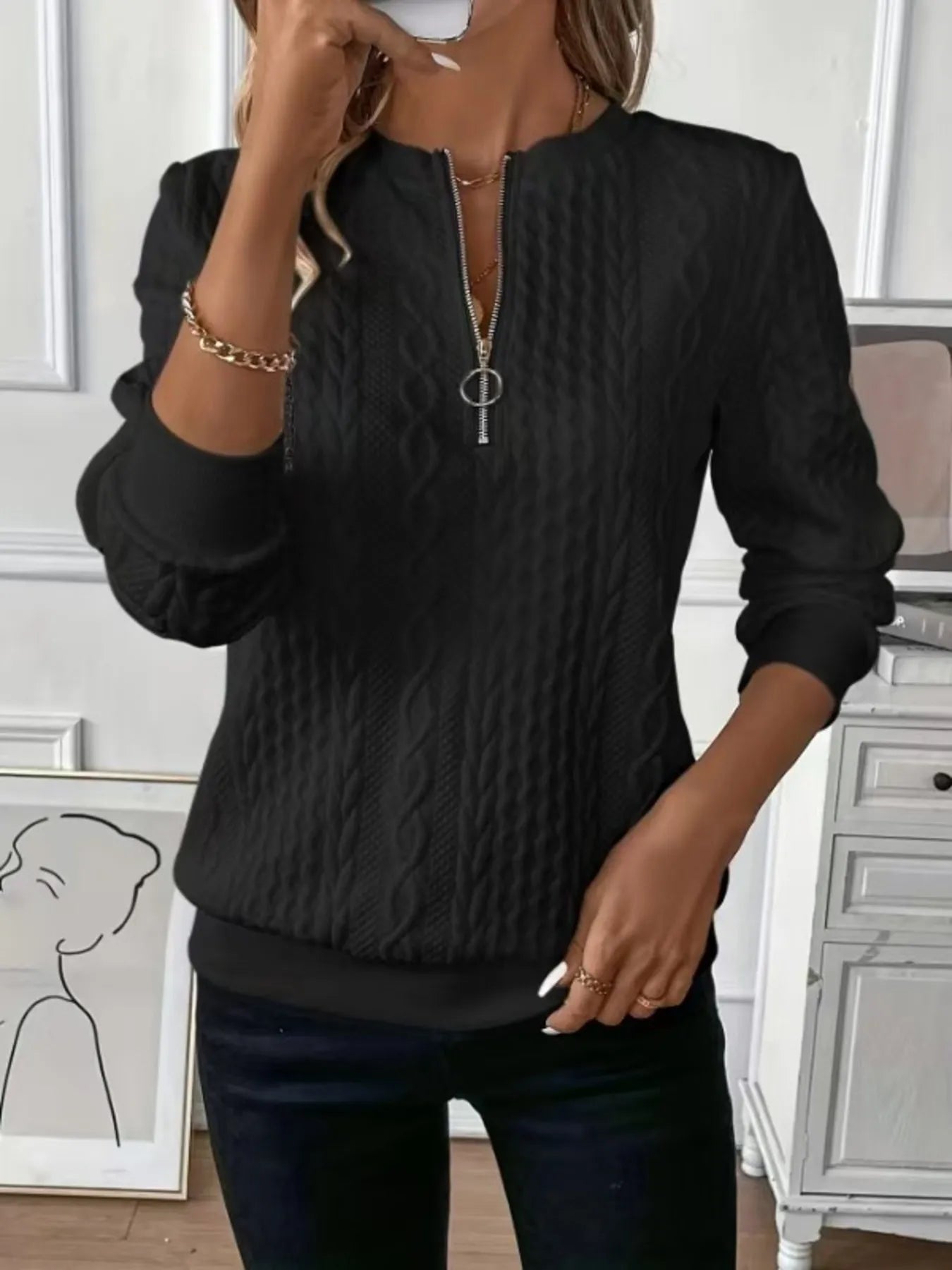 Person wearing a black textured sweater in an indoor setting