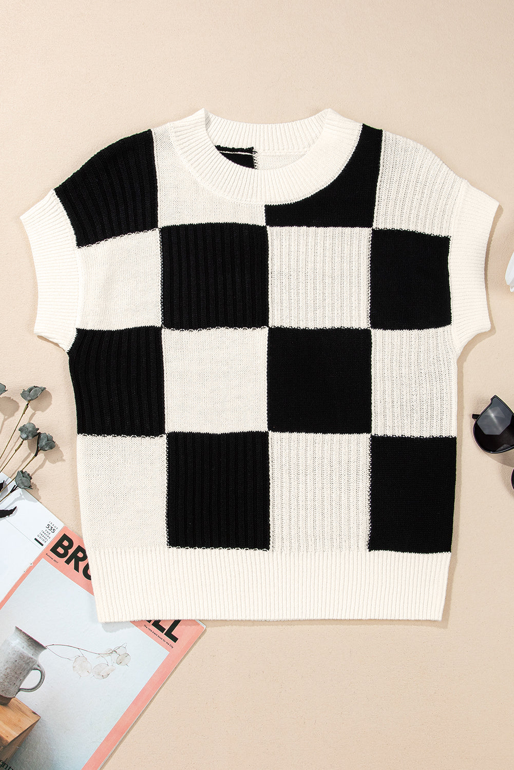 black and white checkered sweater against a pink background