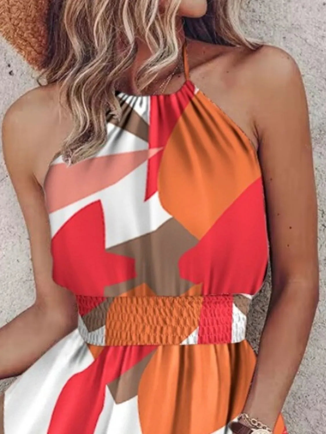 Woman wearing a colorful halter top with geometric pattern on a neutral background