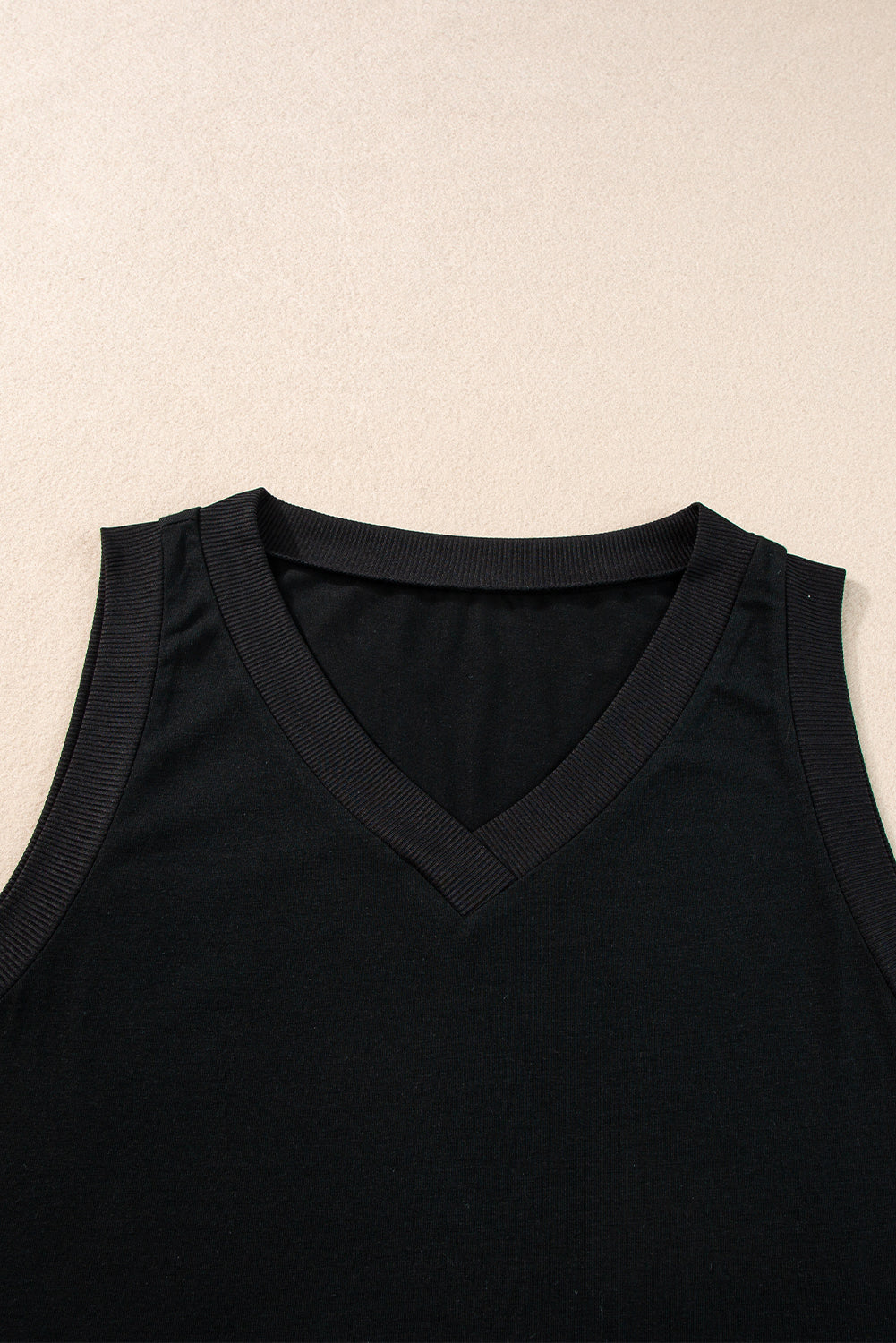 Black sleeveless top on a beige background