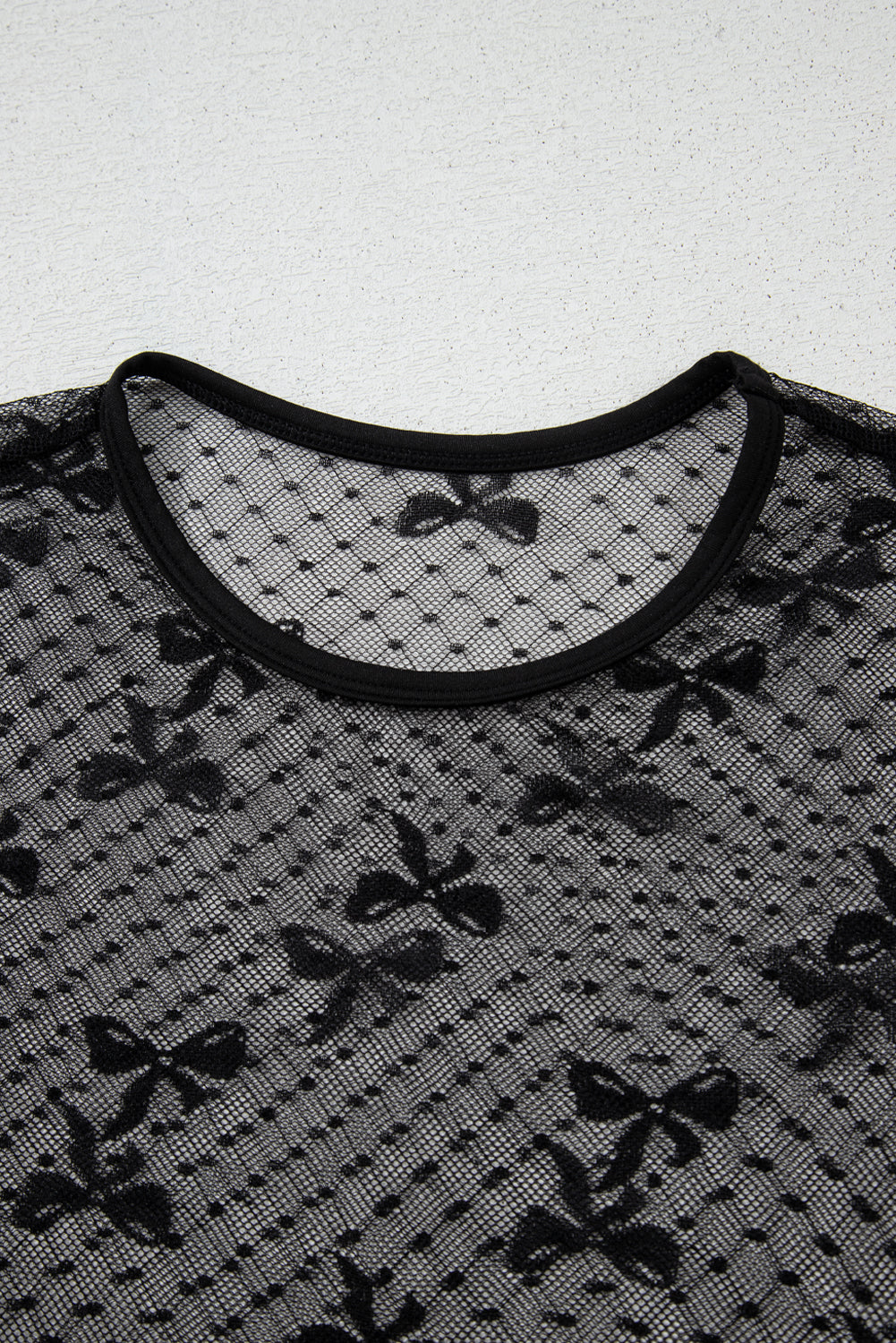 Black mesh top with bow patterns on a white background