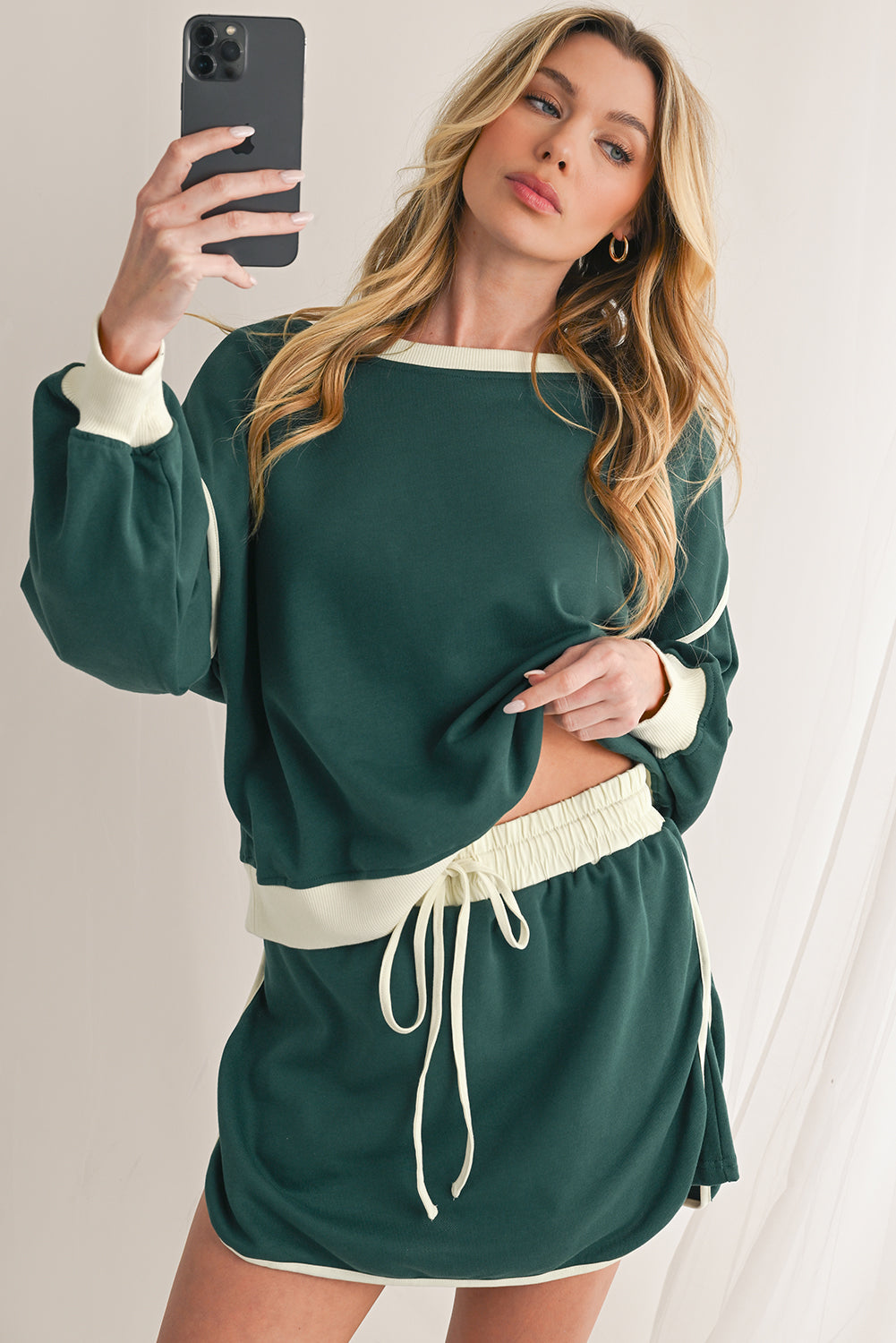 Woman taking a mirror selfie wearing a green and white outfit.
