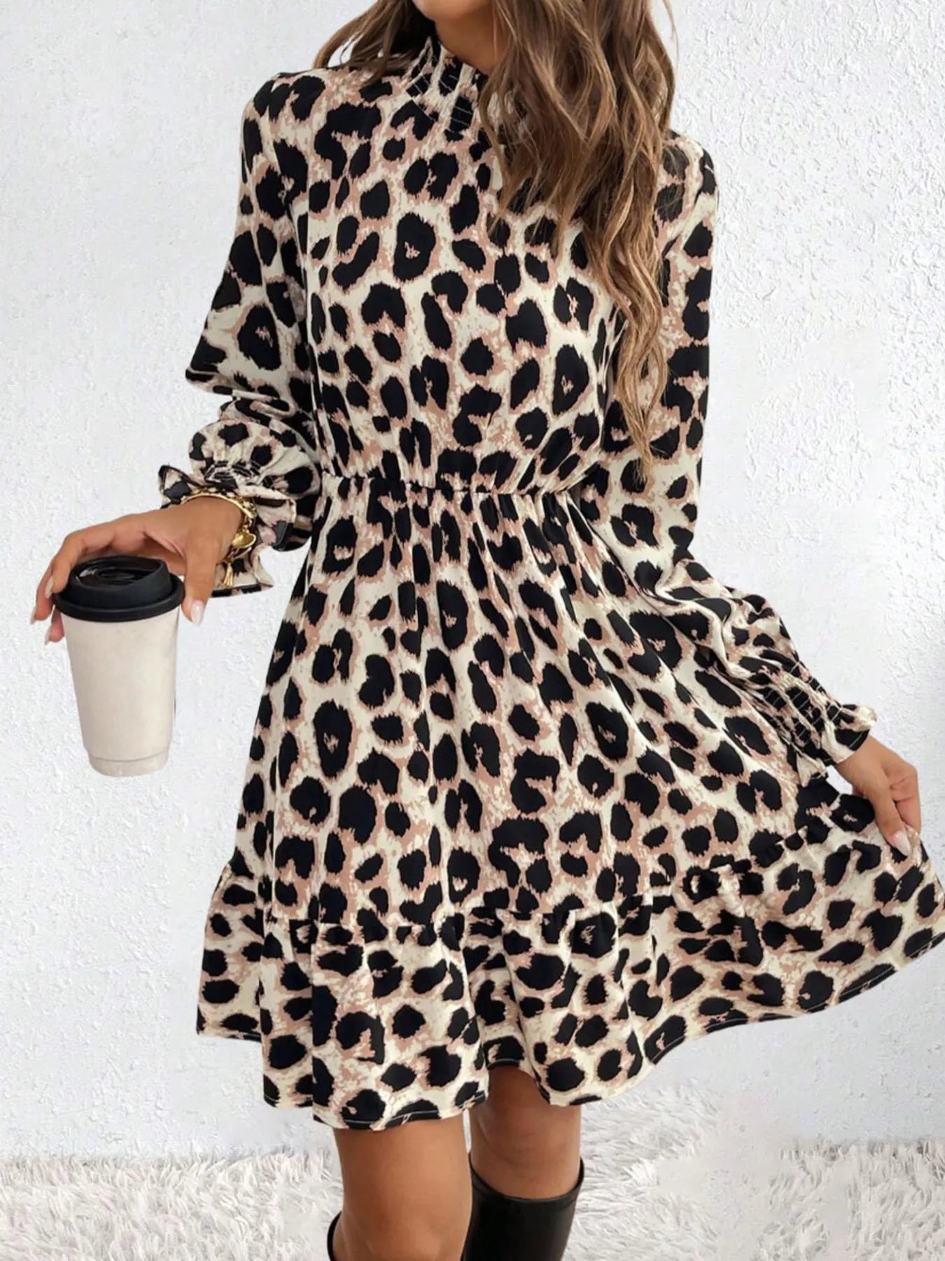 Person wearing a leopard print dress holding a coffee cup against a white background