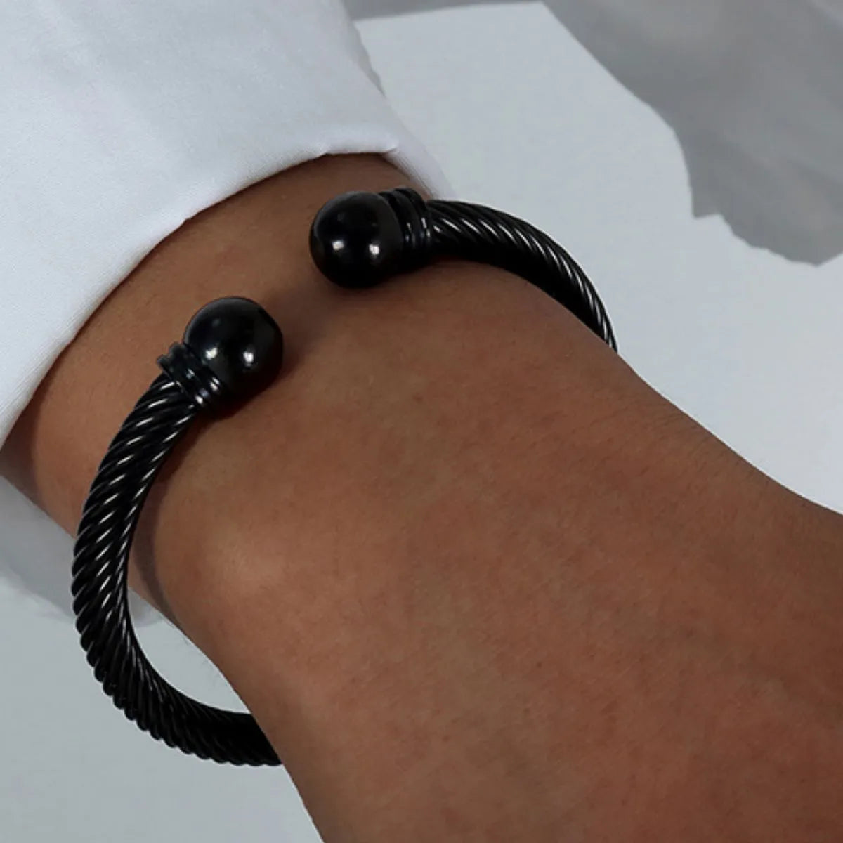 Black braided bracelet on a wrist with a white sleeve