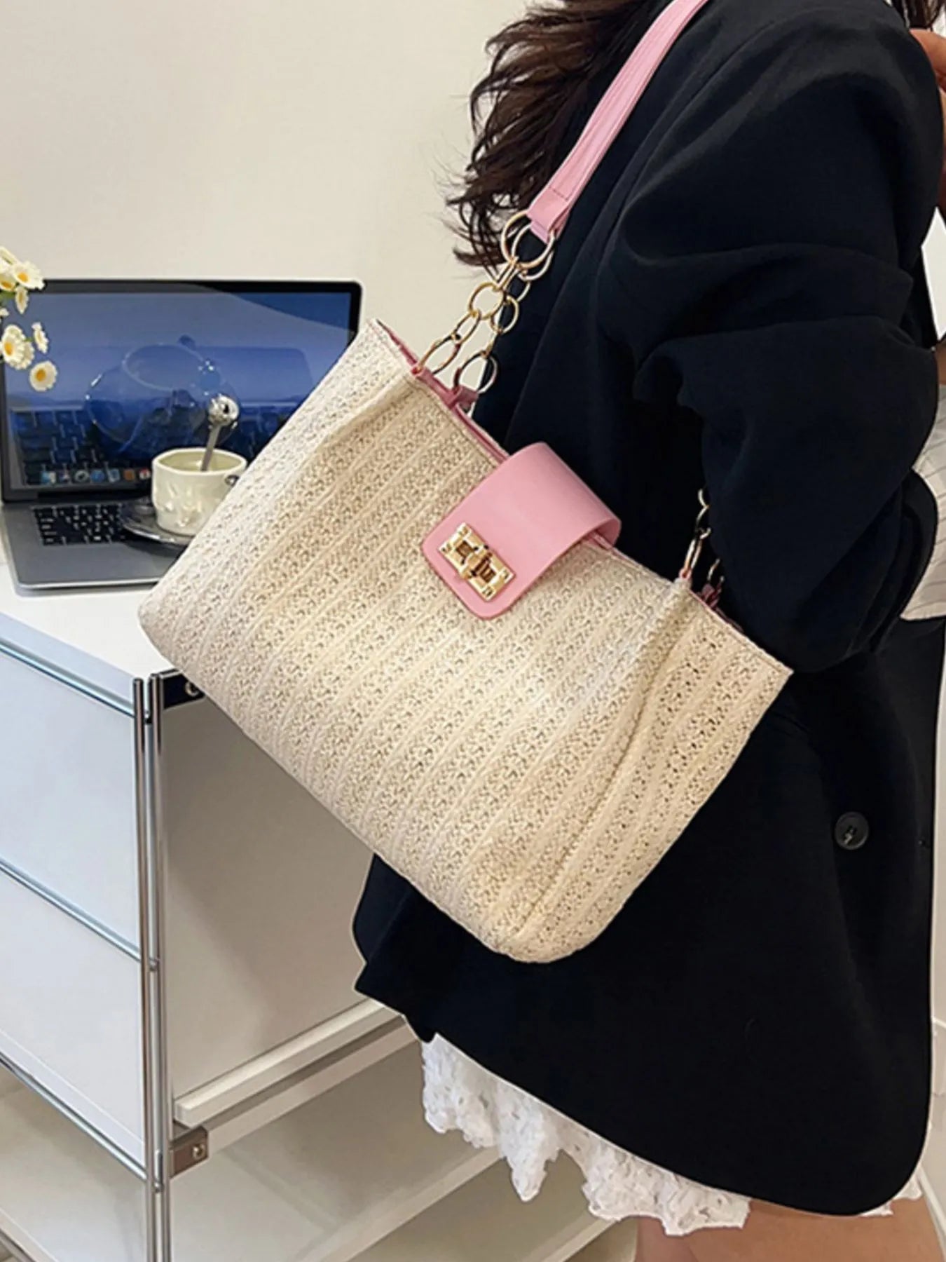 Beige handbag with pink accents on a desk with a laptop