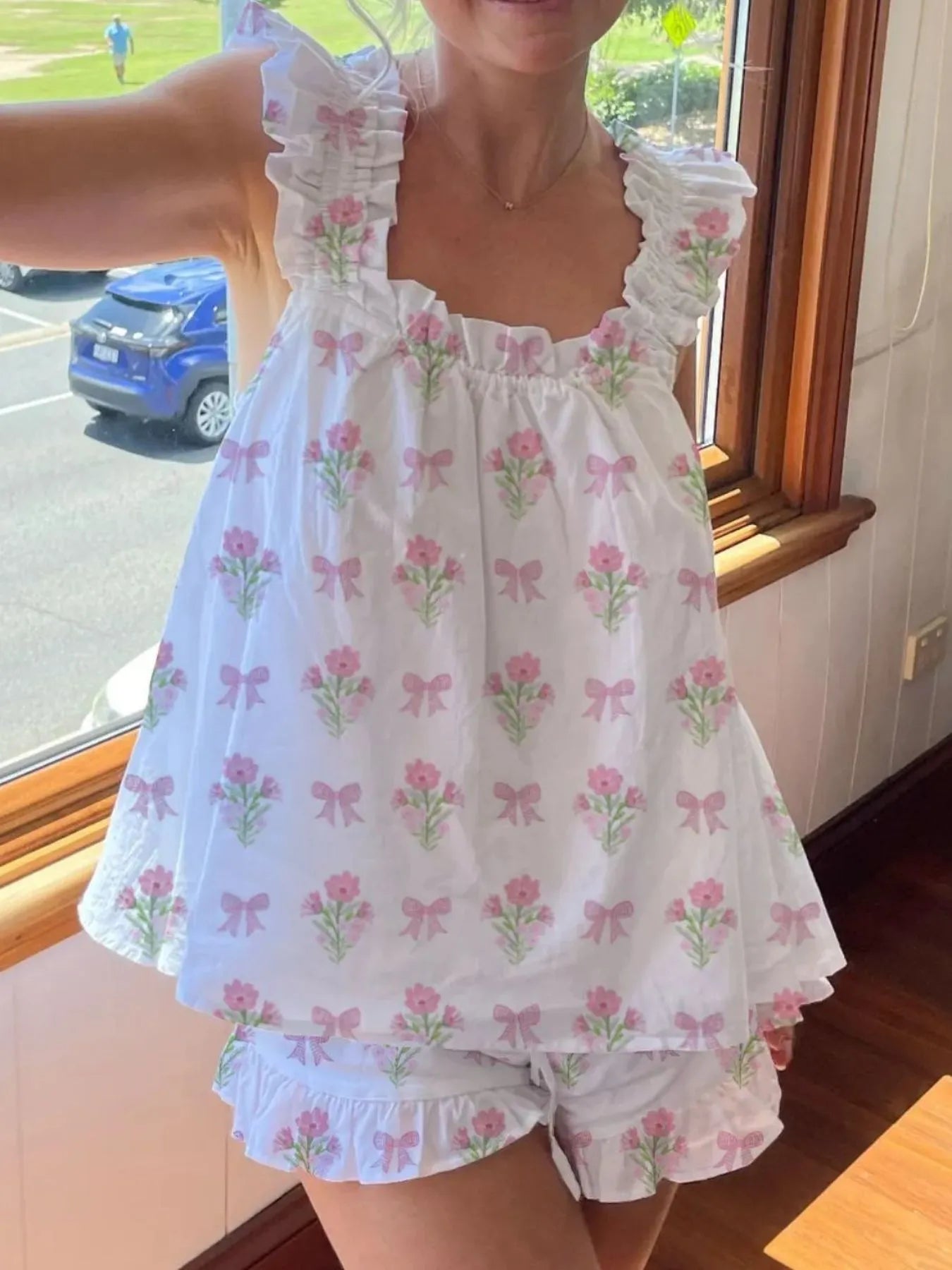 Person wearing a white dress with pink floral patterns indoors.