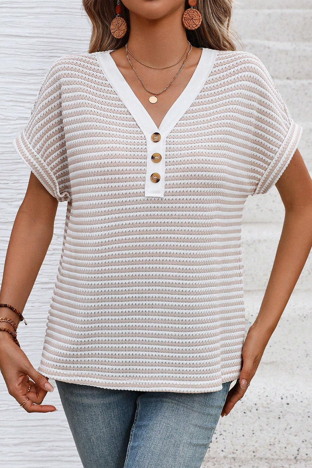 Woman wearing a white textured top with buttons against a light background
