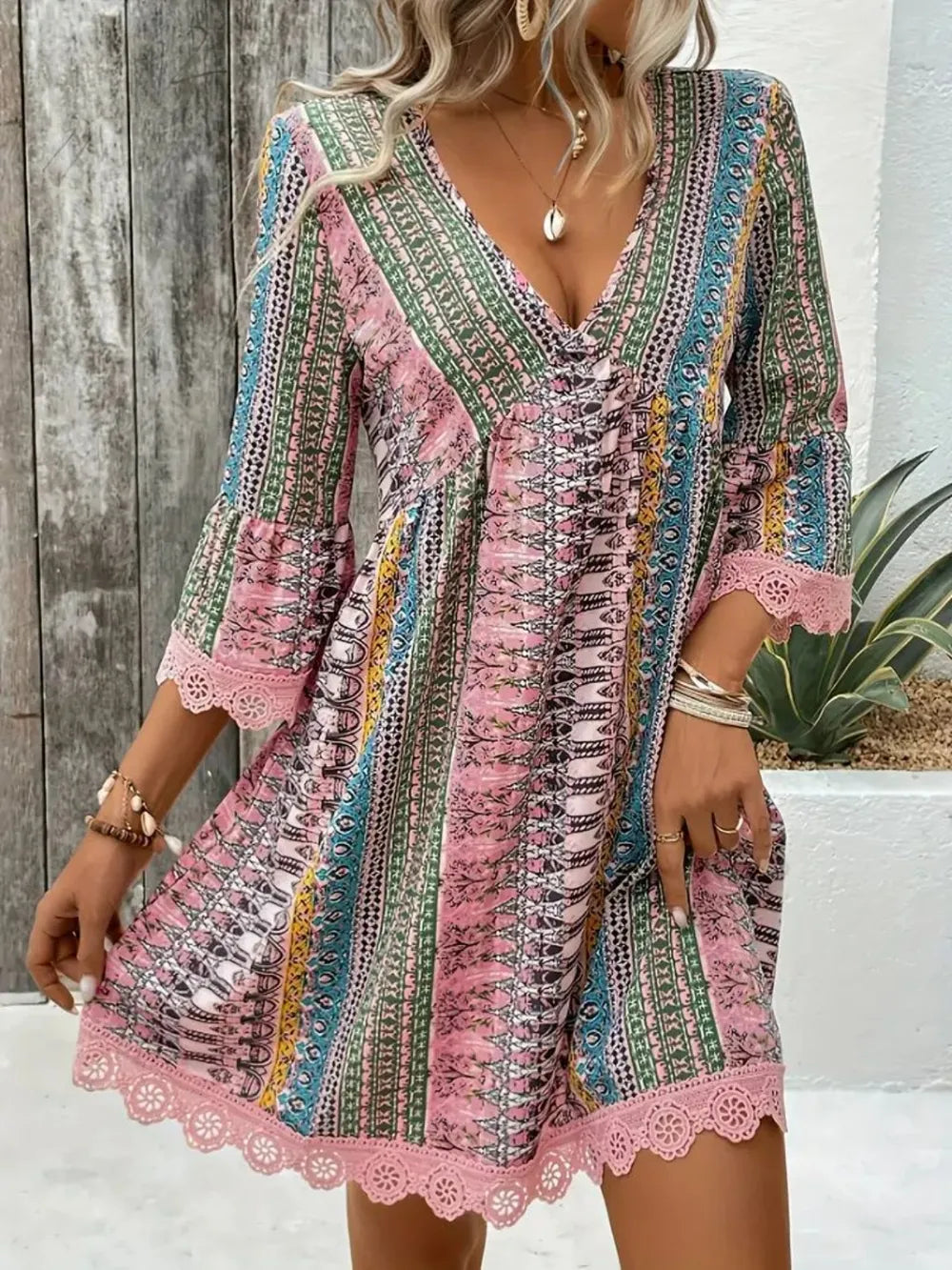 Woman wearing a colorful patterned dress with lace details in an outdoor setting.