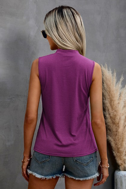 Woman wearing a purple sleeveless top and denim shorts against a gray background