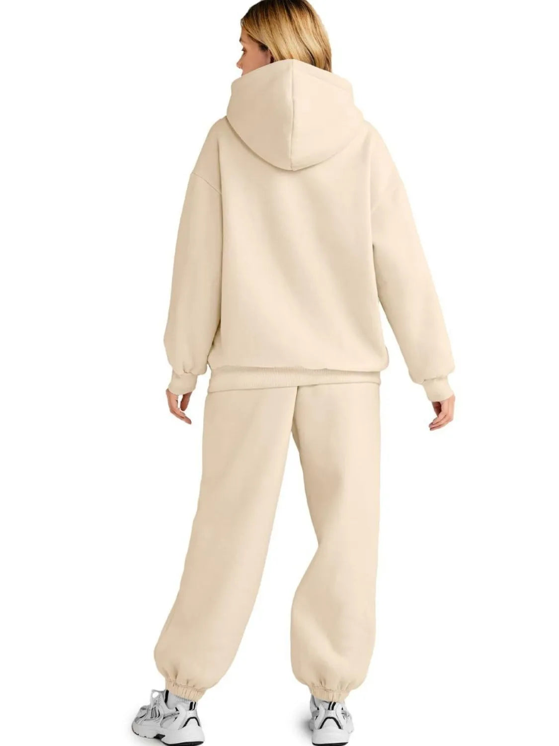 Person wearing a beige tracksuit on a white background