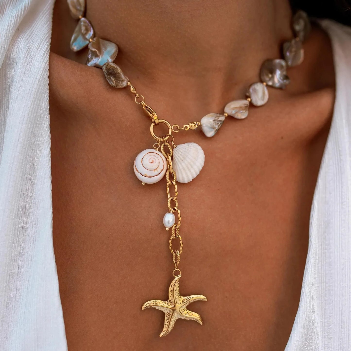 Necklace with shell and starfish charms worn by a person