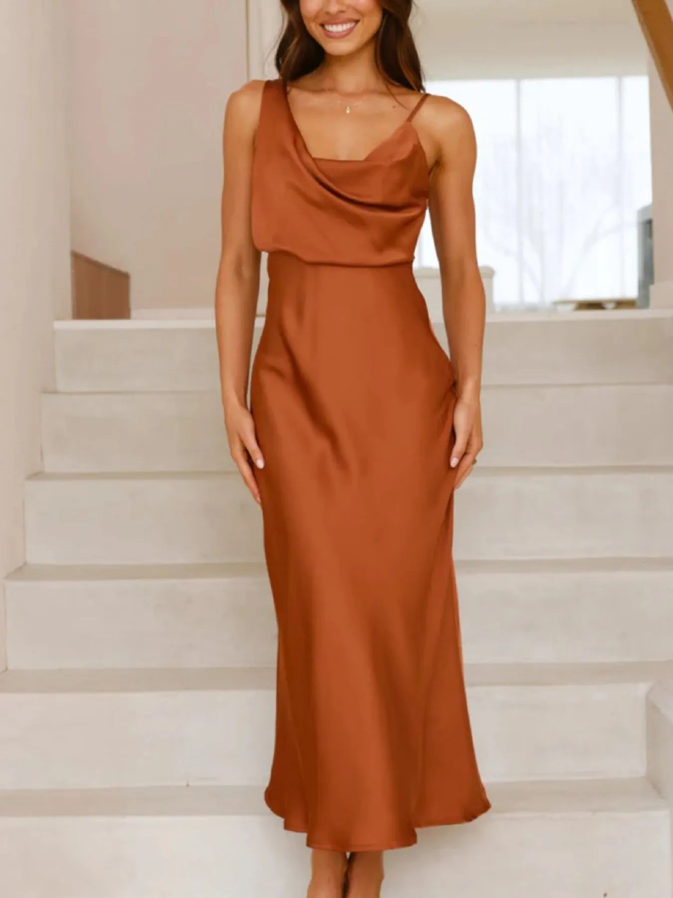 Woman wearing a rust-colored dress standing on a staircase.