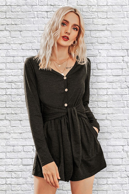 Woman wearing a black dress against a white brick wall