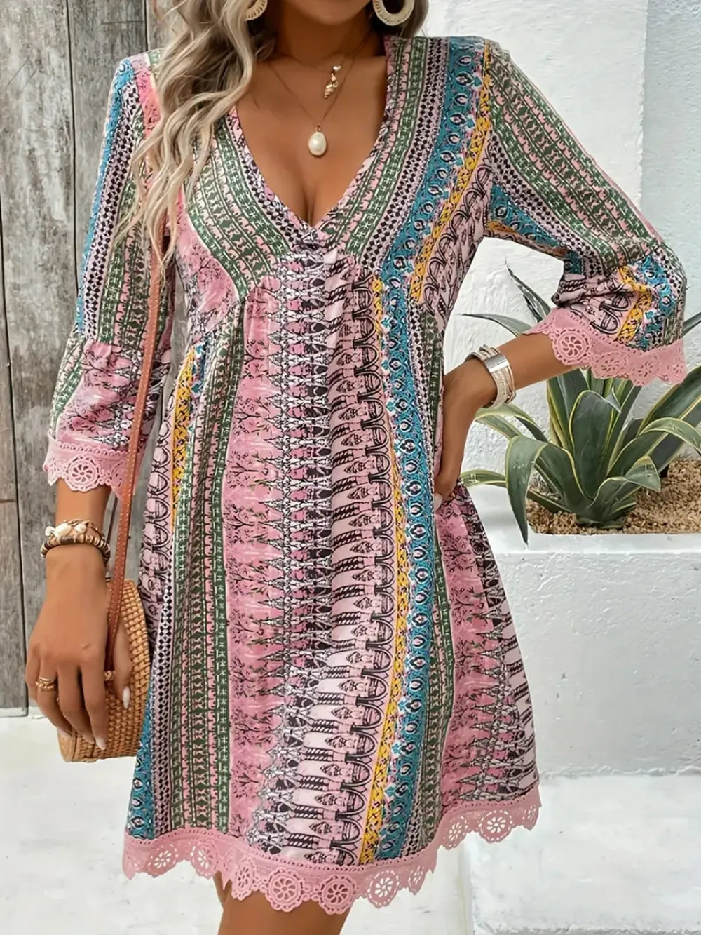 Woman wearing a colorful patterned dress with a wooden floor and plant in the background