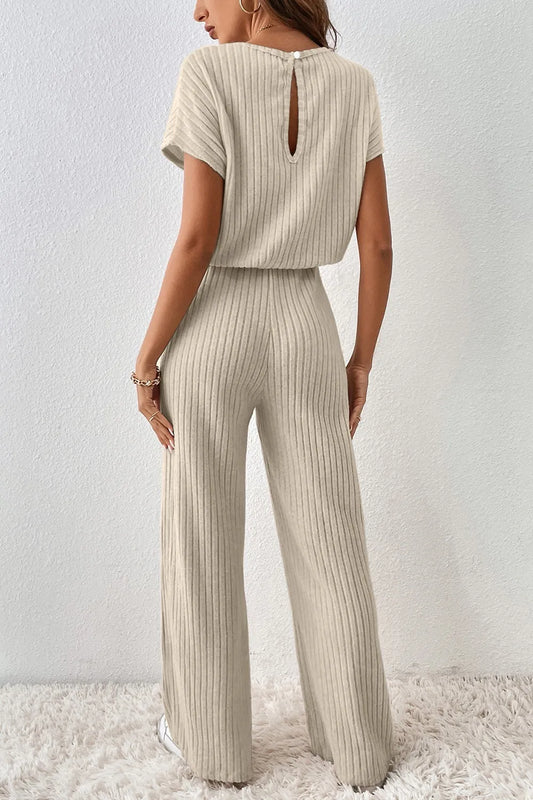 Woman wearing a beige ribbed jumpsuit against a white background
