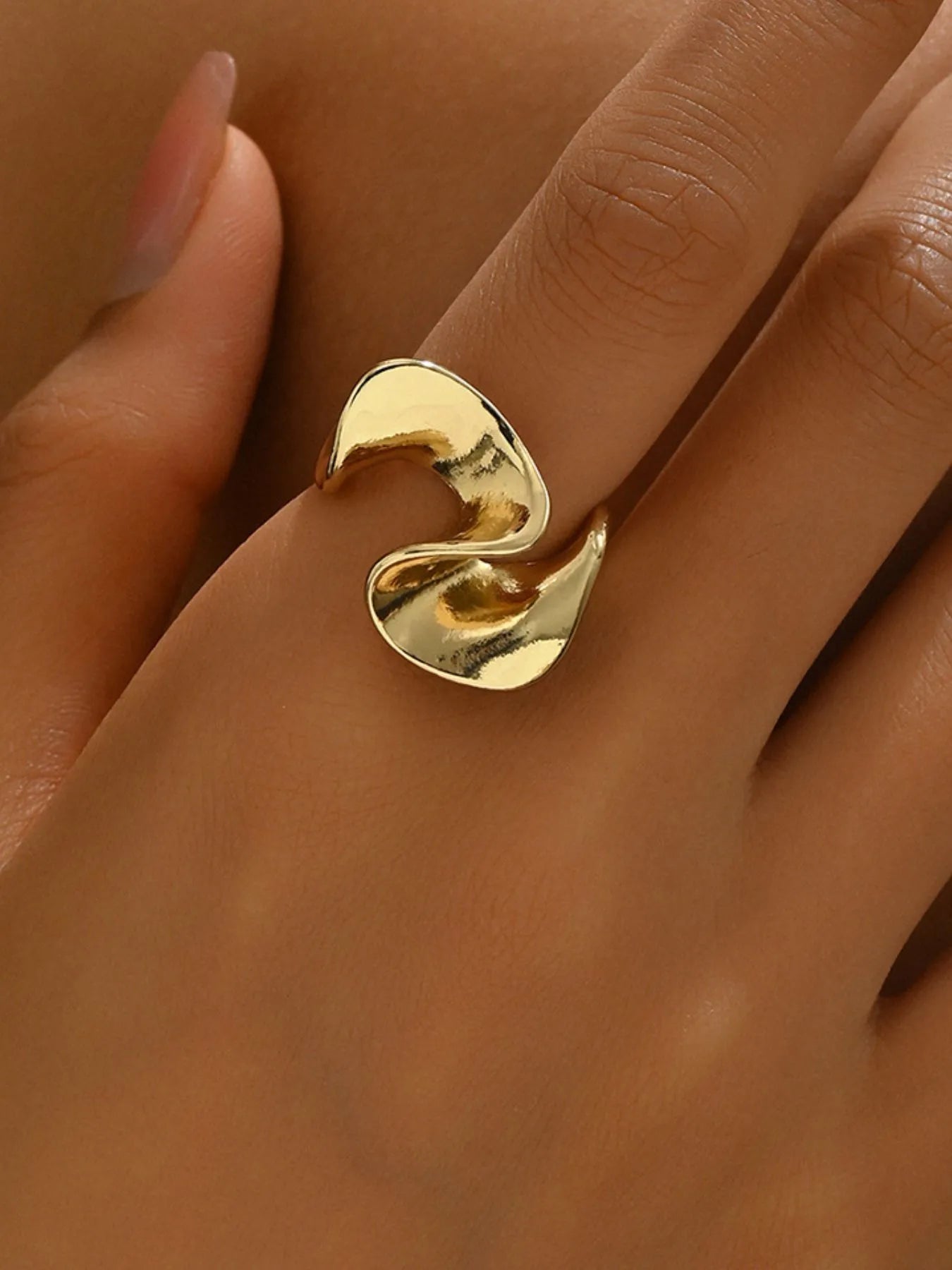 Gold ring on a finger against a neutral background