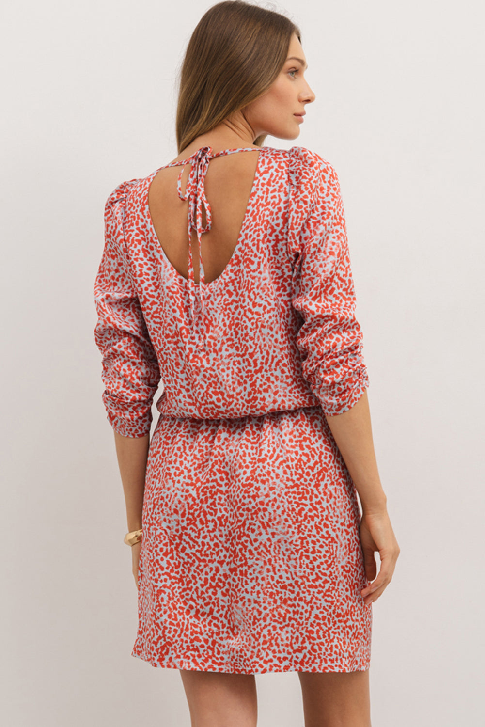 Woman wearing a red and white patterned dress with a plain background