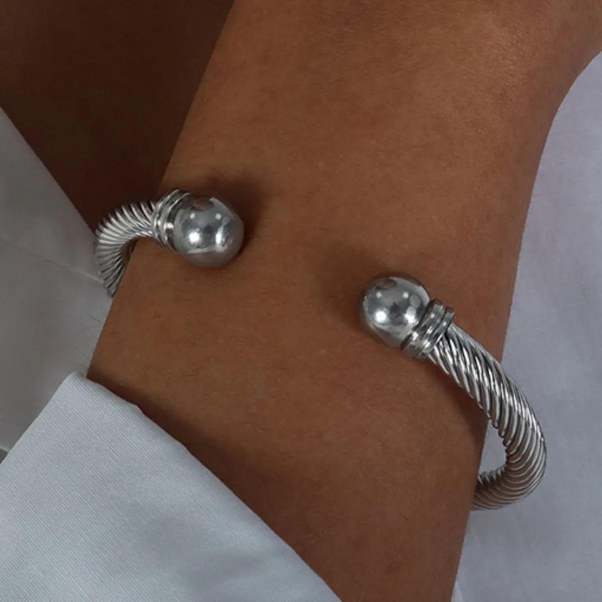 Silver bracelet on a wrist with a neutral background