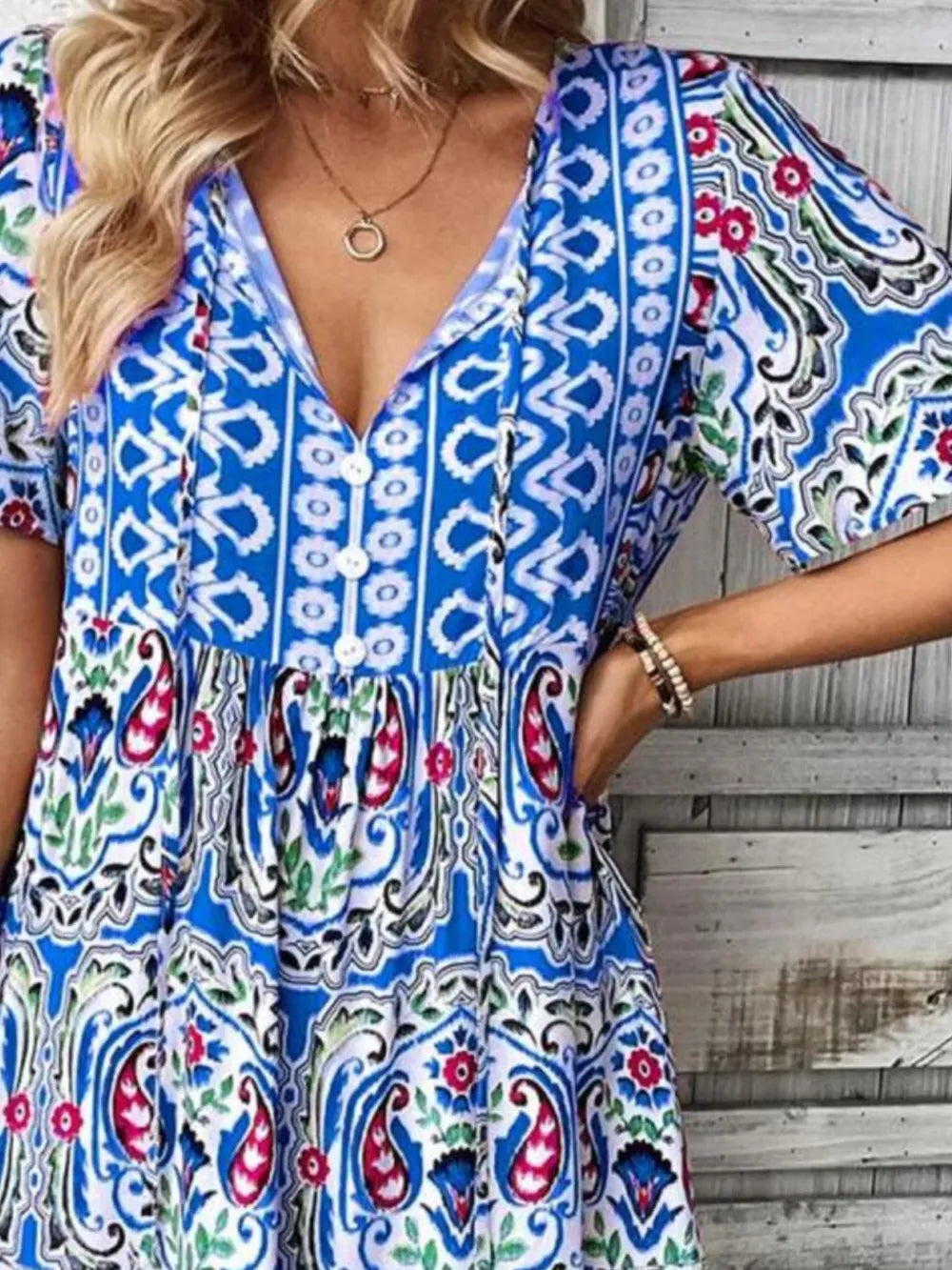 Woman wearing a colorful patterned dress with a wooden background
