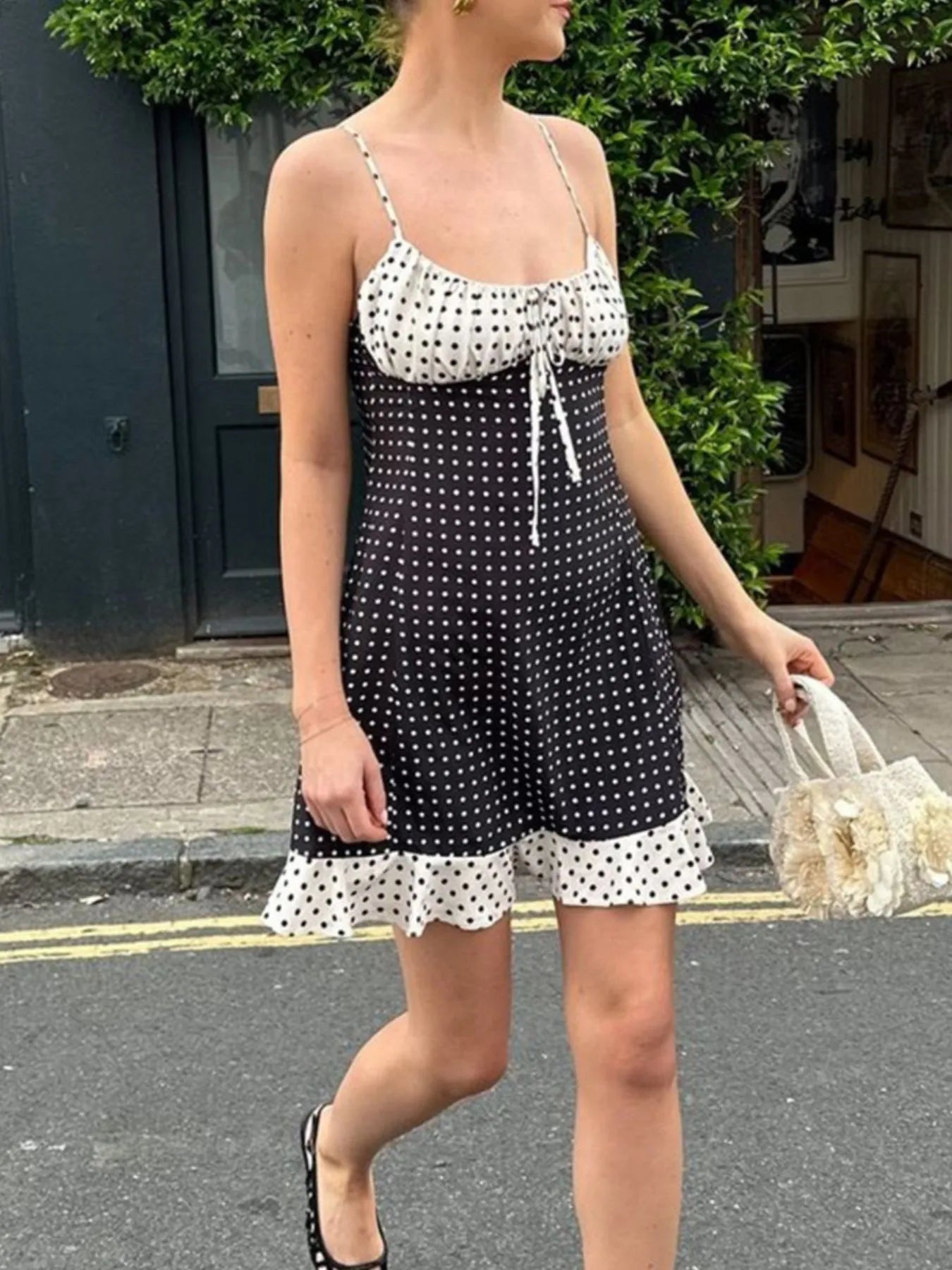 Woman wearing a black and white polka dot dress on a street.