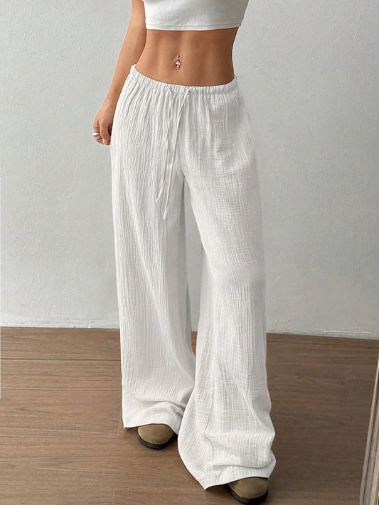 Person wearing white wide-leg pants against a plain background
