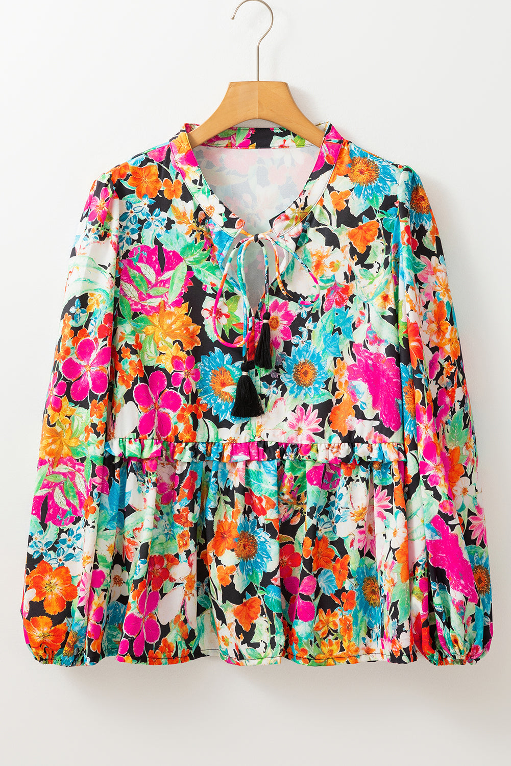 Colorful floral blouse on a hanger against a white background