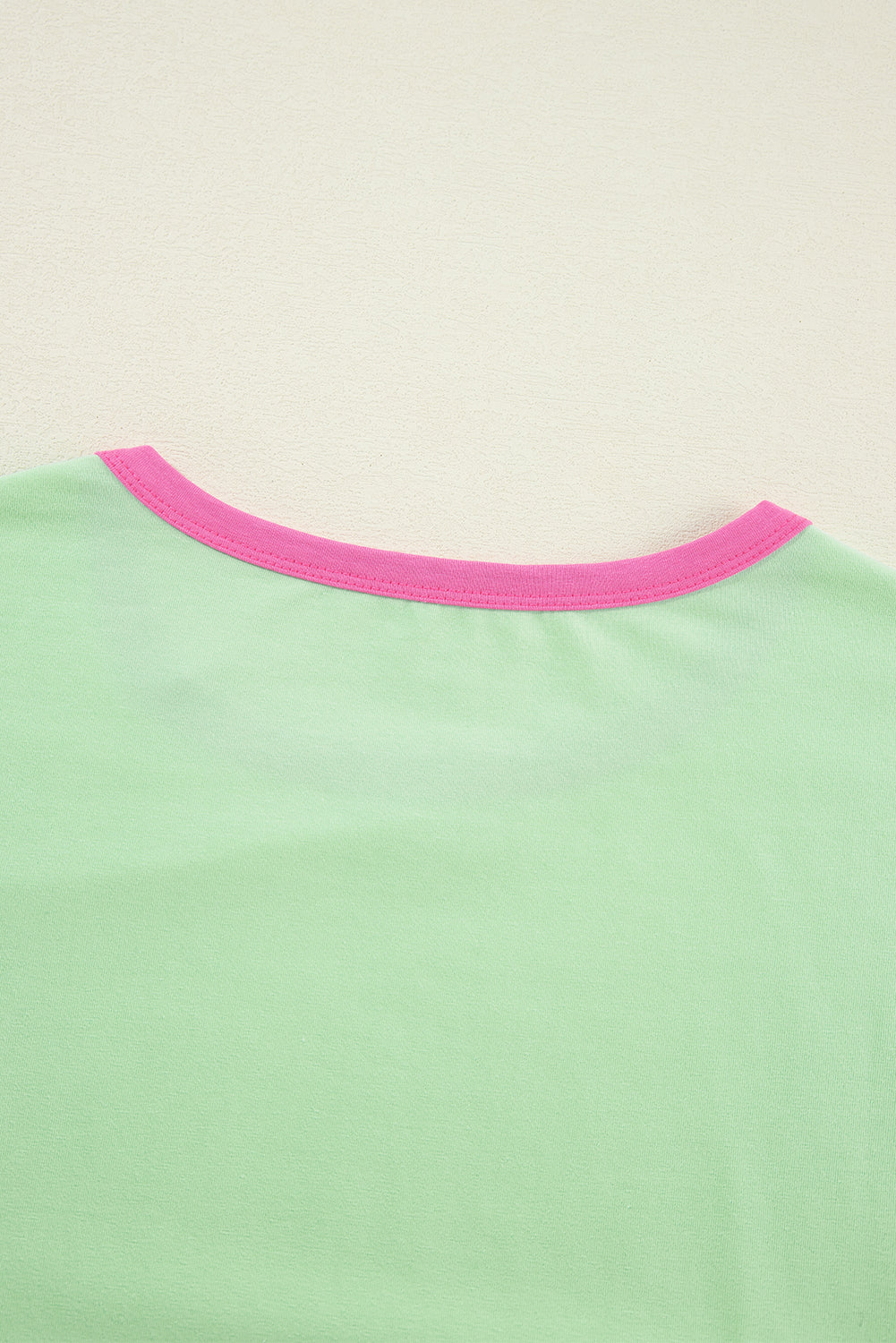 Green shirt with pink neckline on a beige background