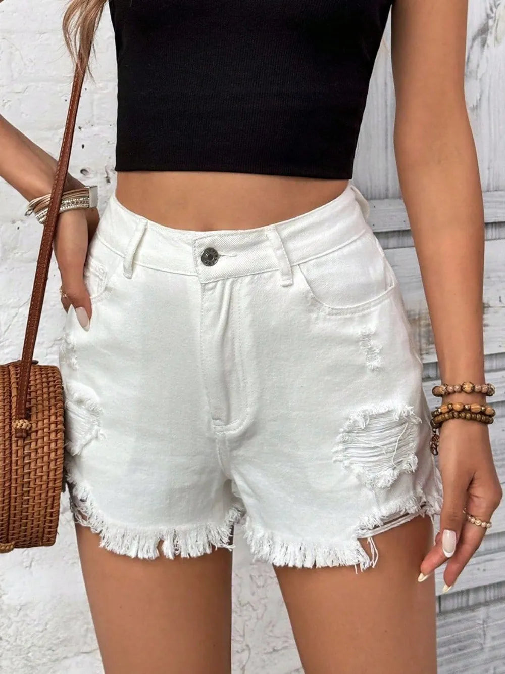 Person wearing white denim shorts and a black crop top against a light background