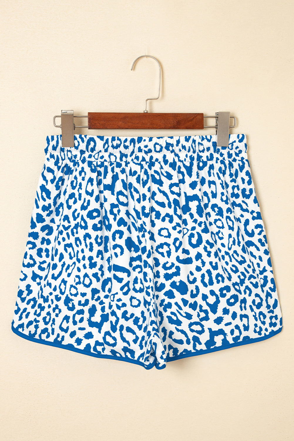 Blue leopard print shorts on a hanger against a beige background