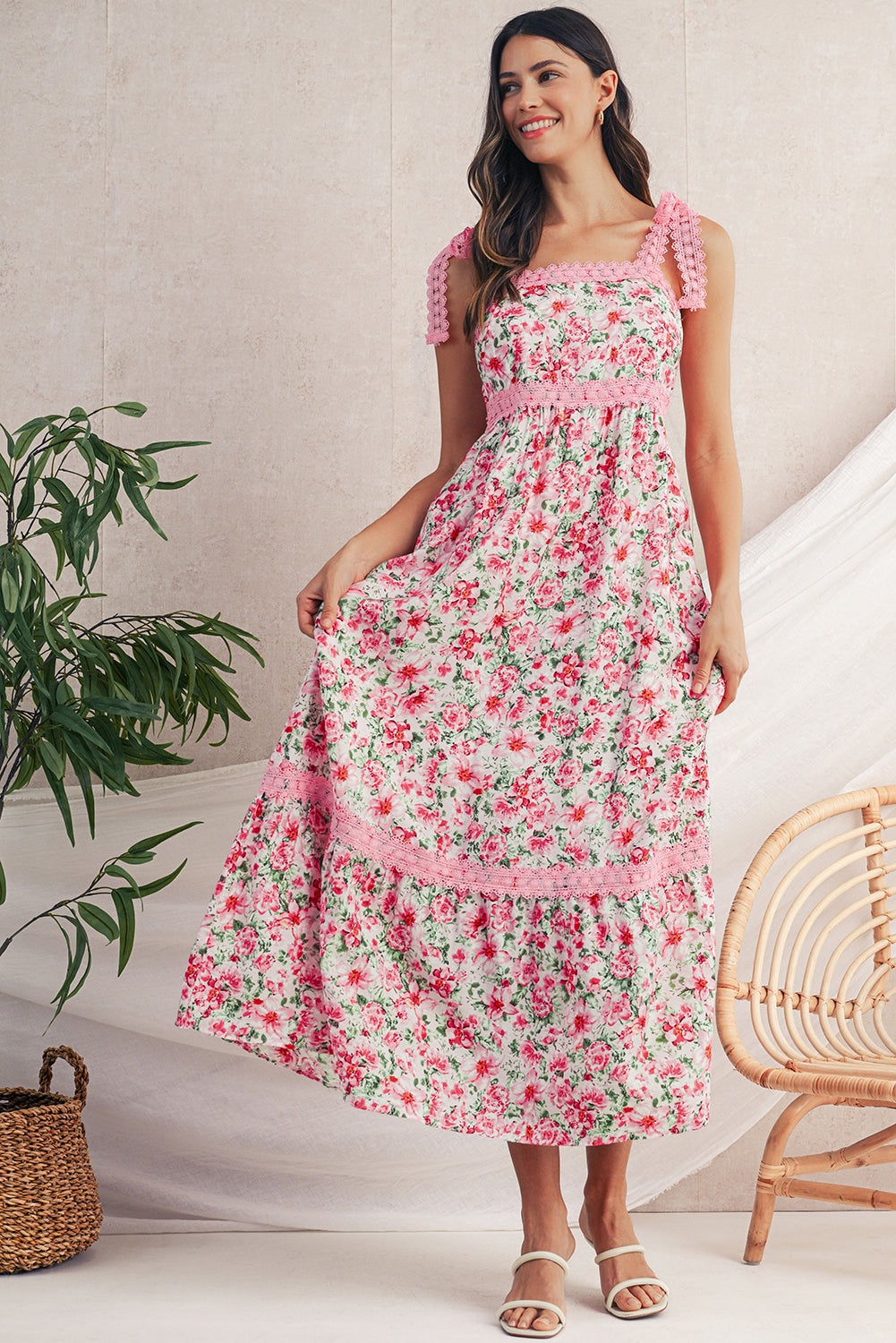 Woman wearing a pink floral dress in a home setting with a plant and chair.