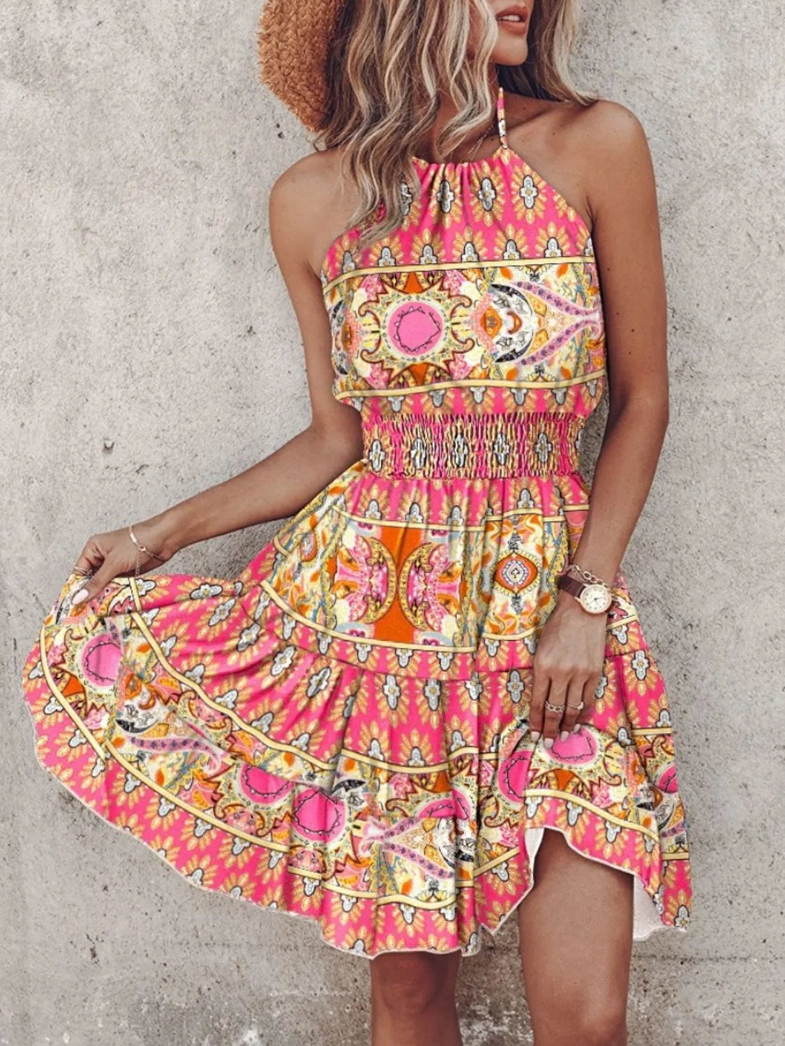 Woman wearing a colorful patterned dress against a concrete wall.