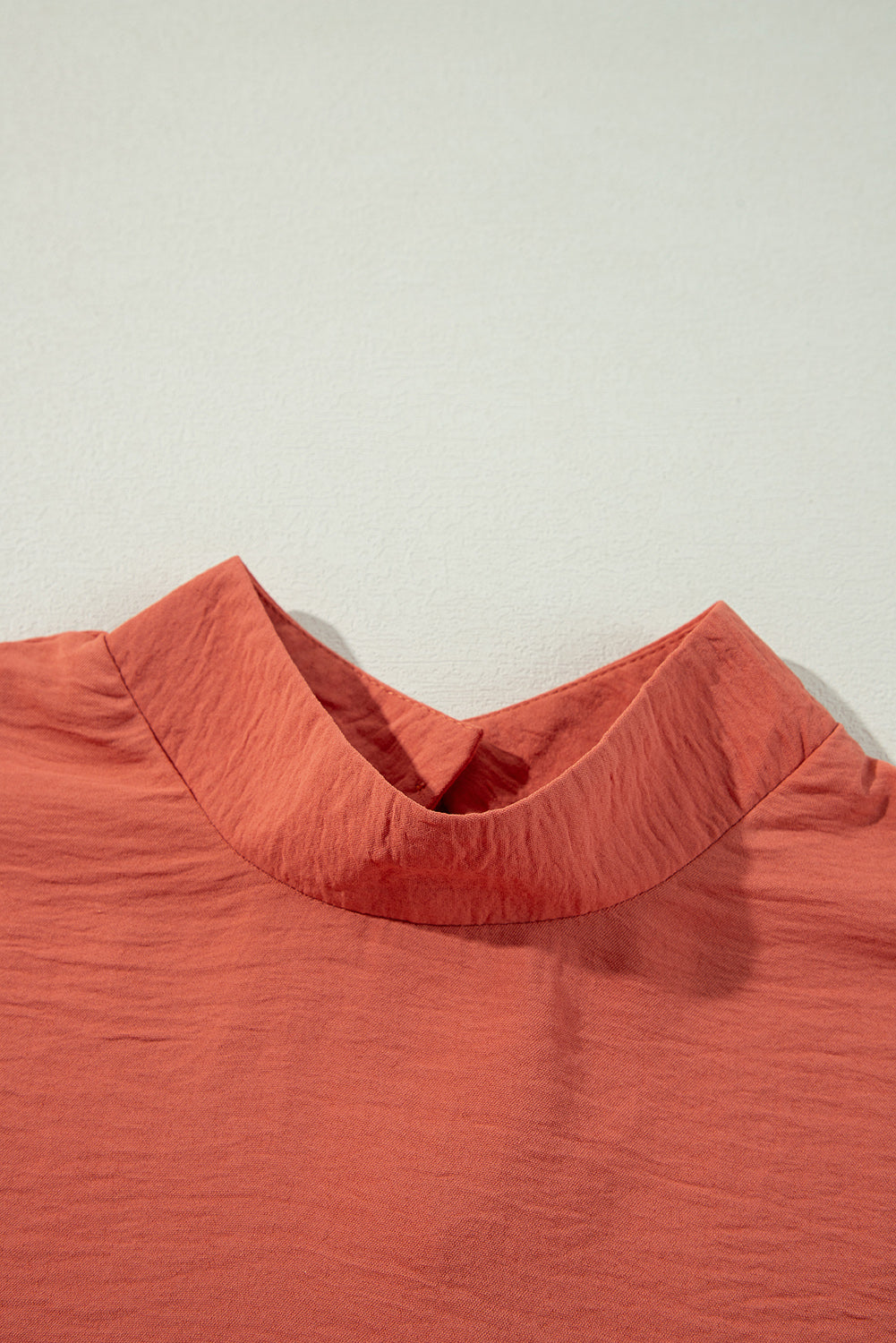 Close-up of a rust-colored shirt with a collar on a light gray background