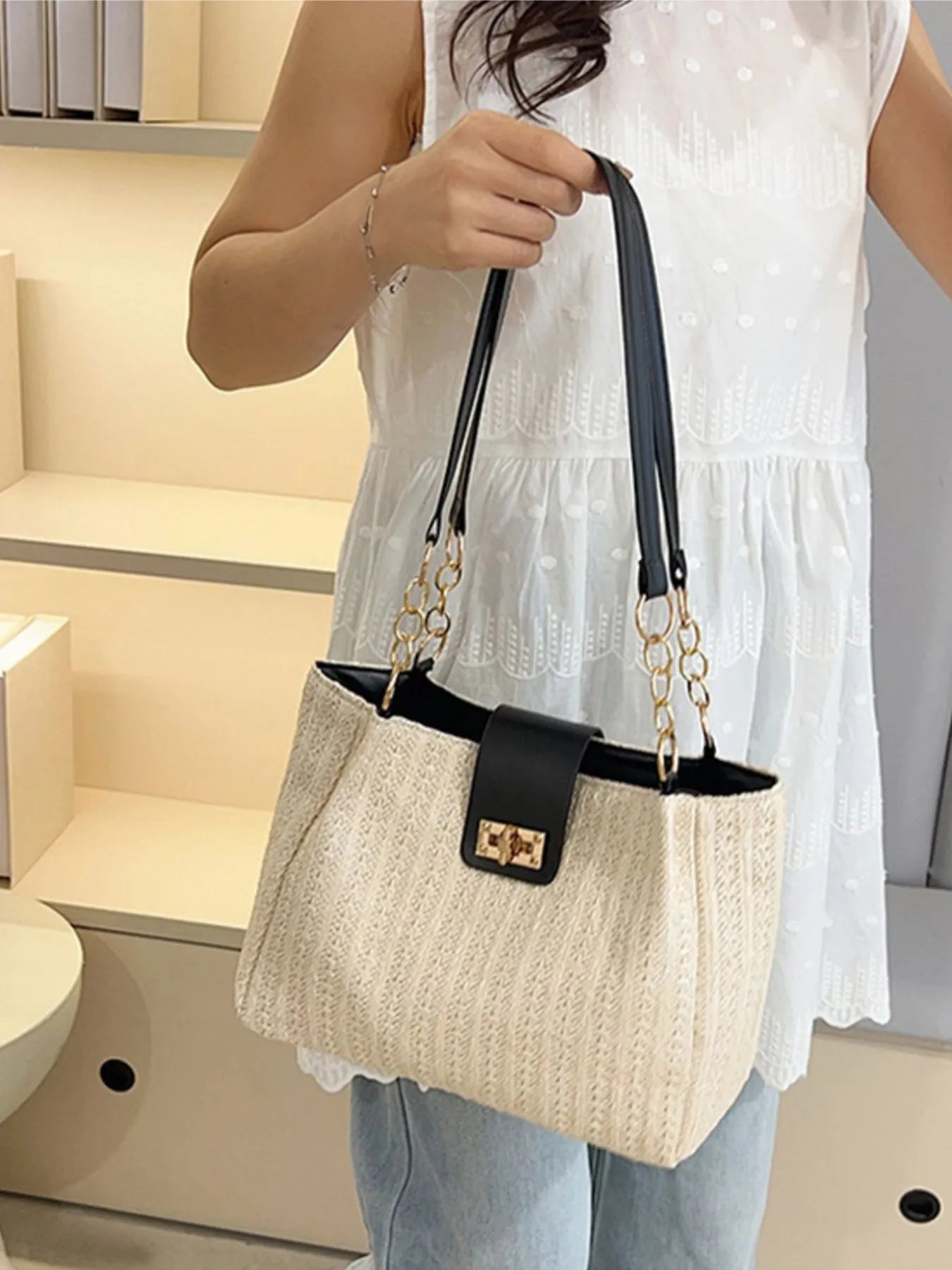 Person holding a black and beige handbag in an indoor setting