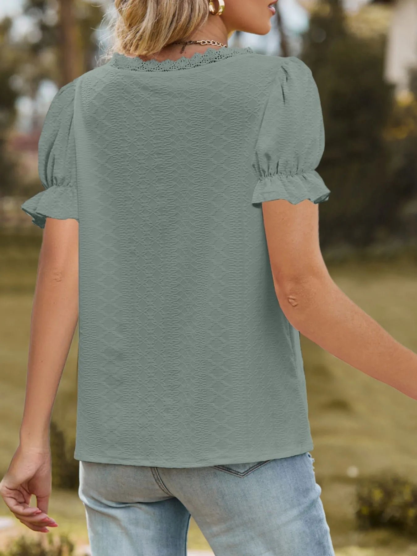 Person wearing a green blouse with ruffled sleeves in an outdoor setting