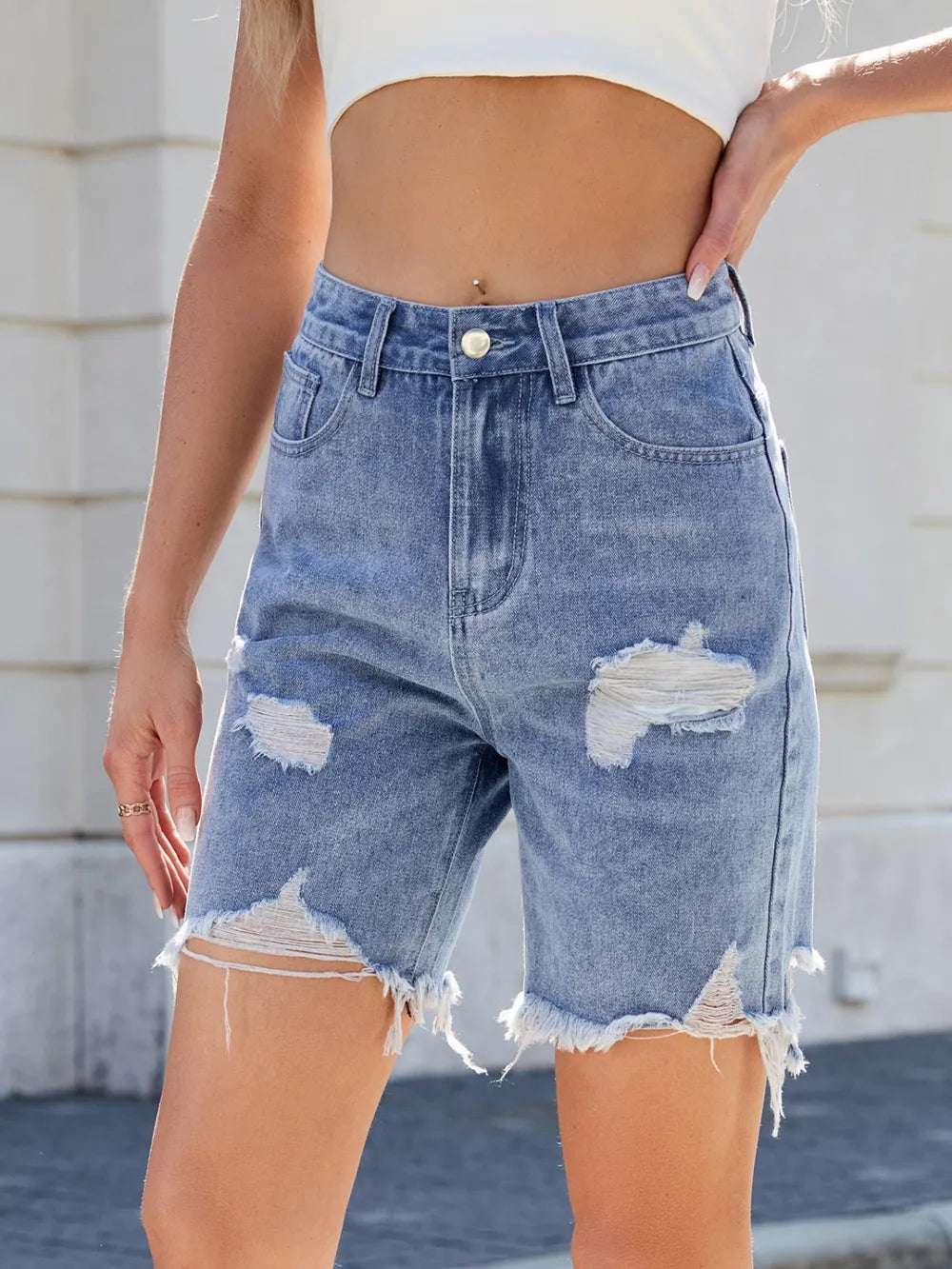 Person wearing distressed denim shorts with a blurred background
