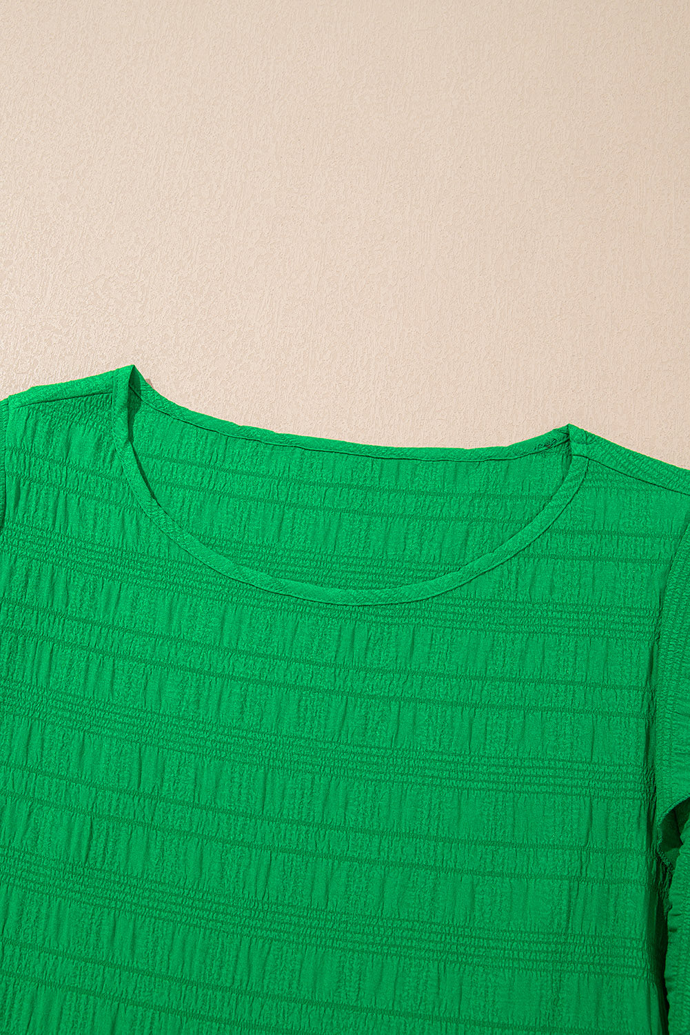Close-up of a green textured shirt on a beige background