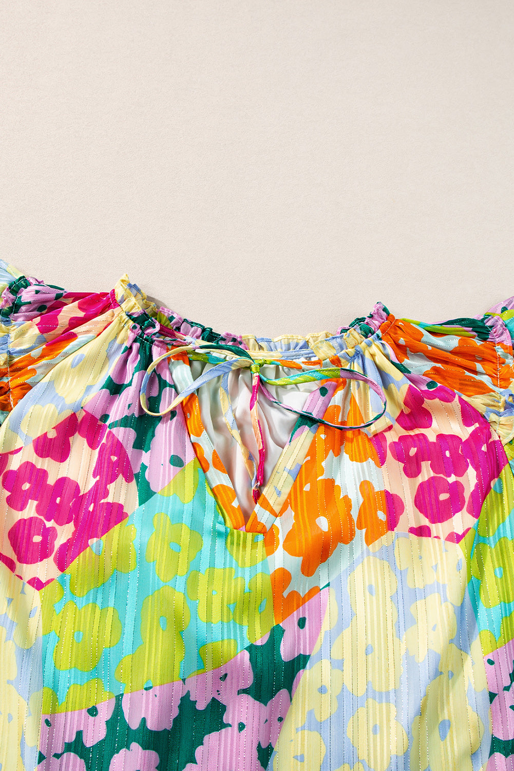 Colorful floral dress with a tie waist on a beige background