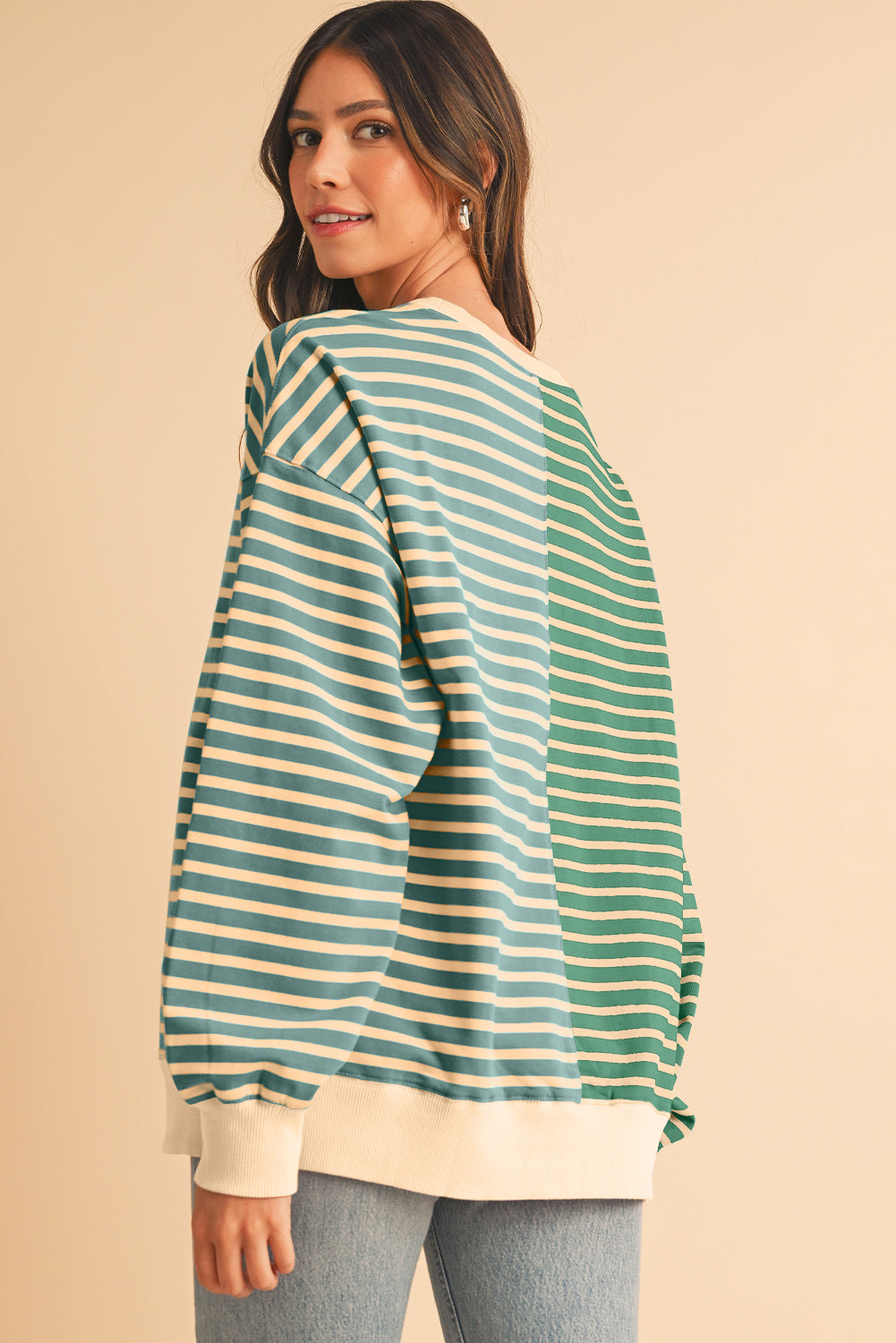 Woman wearing a green and white striped sweater on a beige background