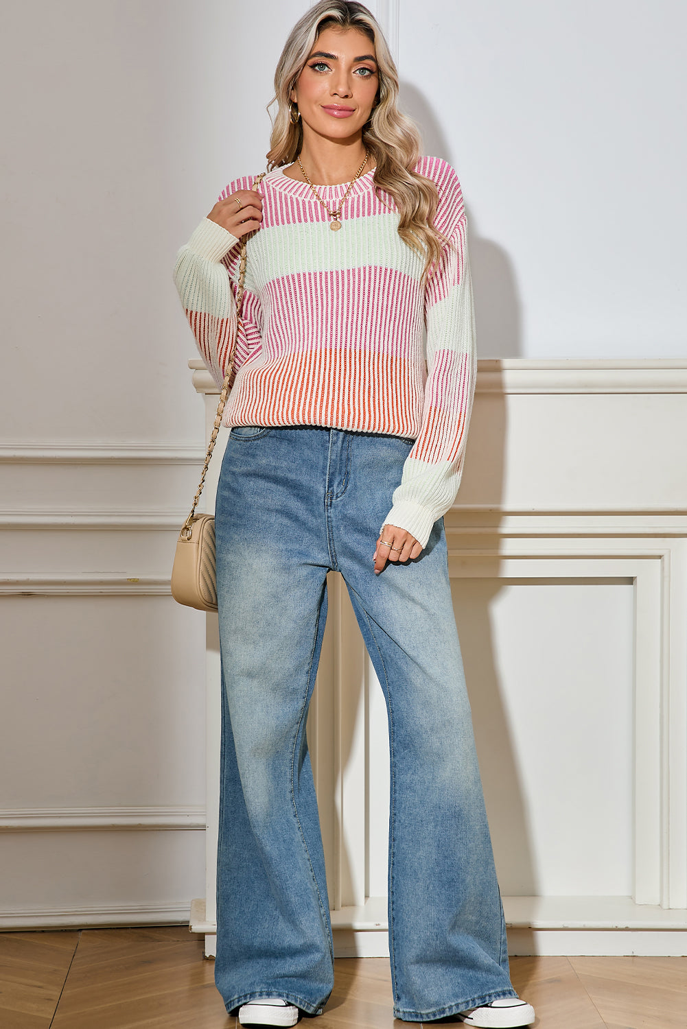 Woman wearing a colorful striped sweater and blue jeans standing against a neutral background