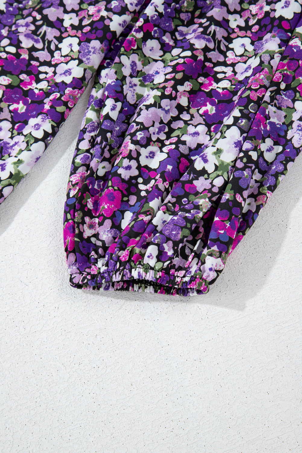 Floral-patterned fabric with purple and pink flowers on a white background
