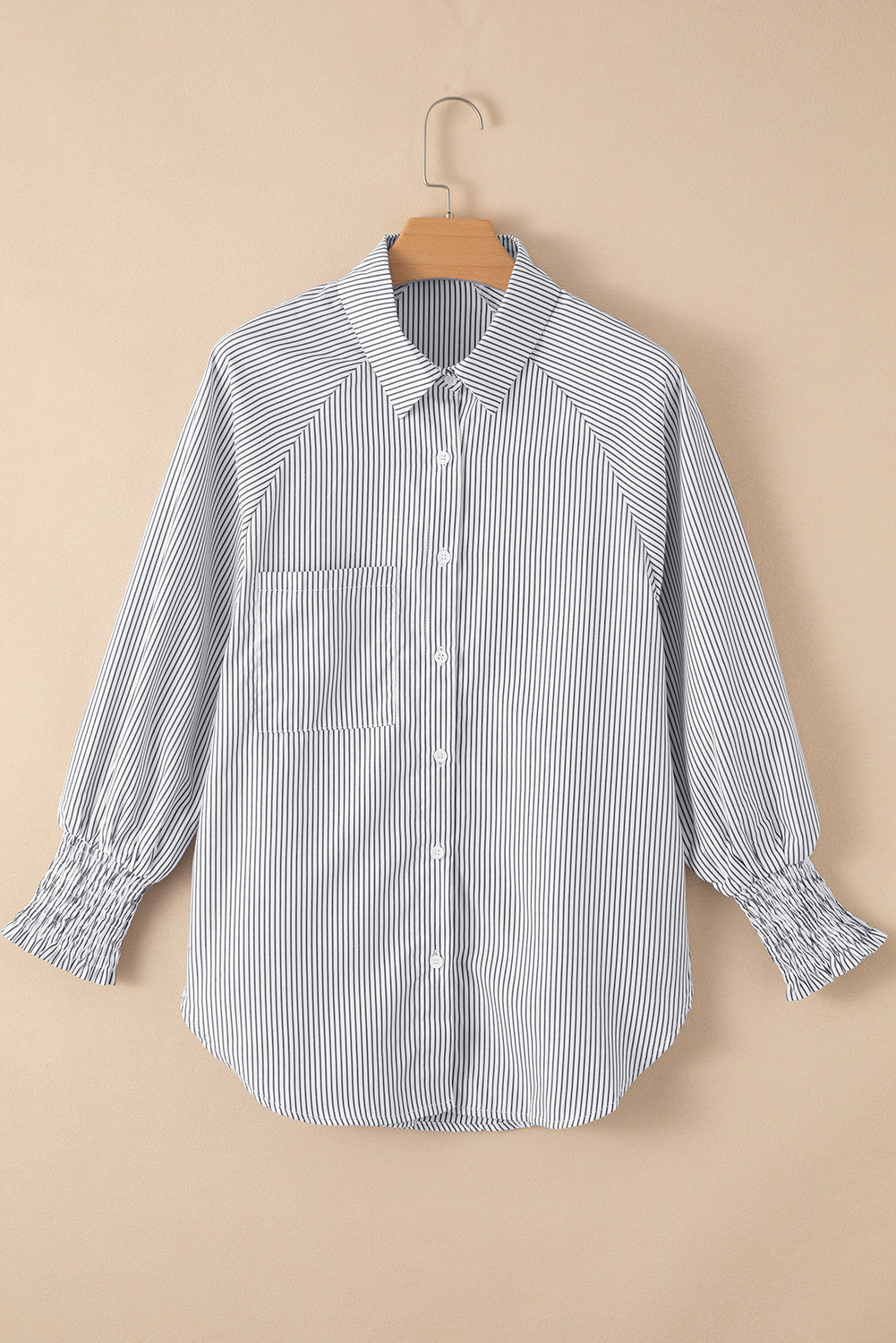 Blue and white striped shirt on a hanger against a beige background