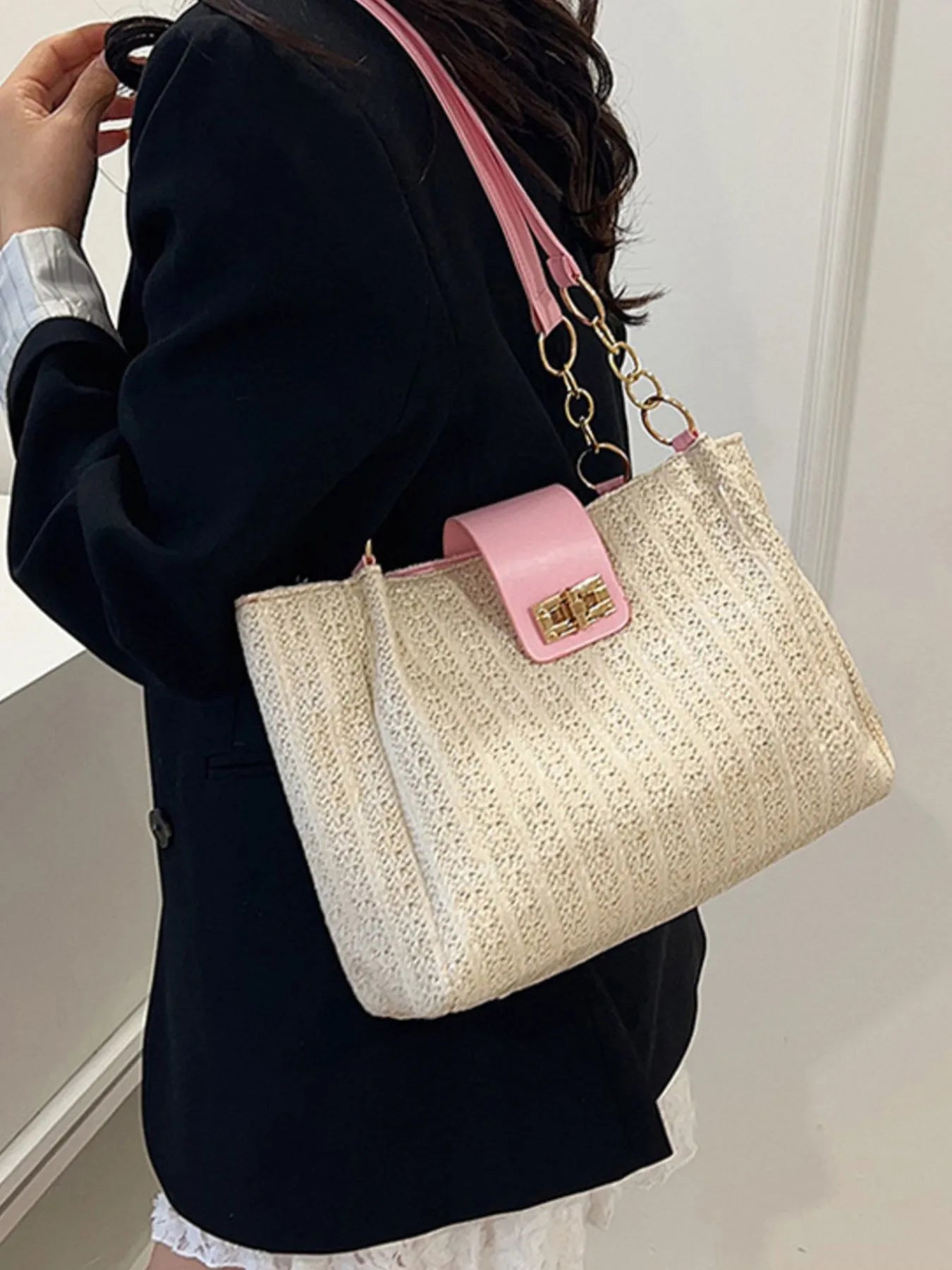 Person holding a beige handbag with pink accents against a neutral background