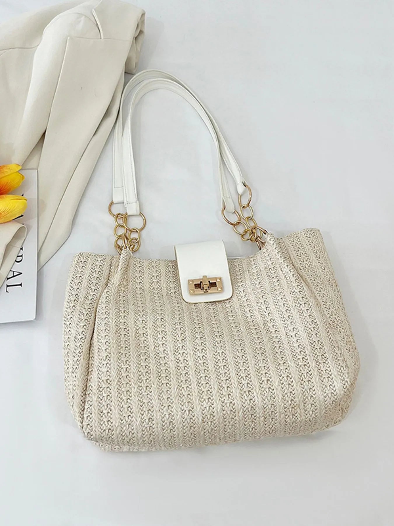 Beige woven handbag with gold accents on a light gray background