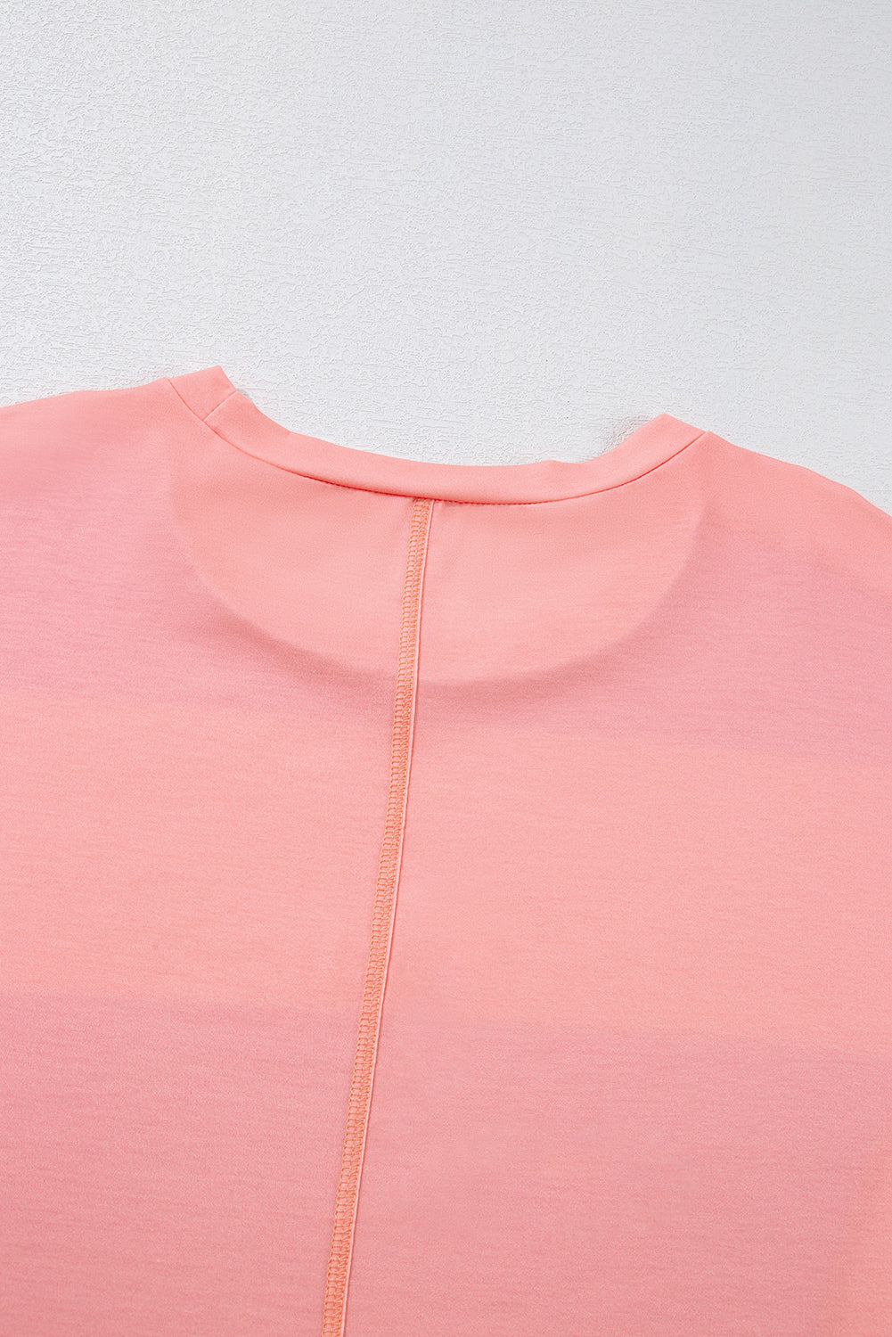 Close-up of a pink garment with a zipper on a light gray background