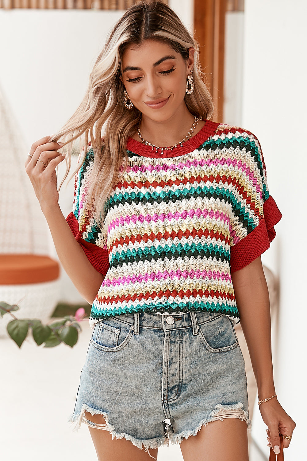 Woman wearing a colorful striped shirt and denim shorts indoors.