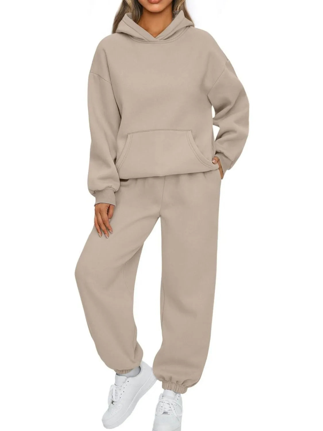 Person wearing a beige tracksuit on a white background